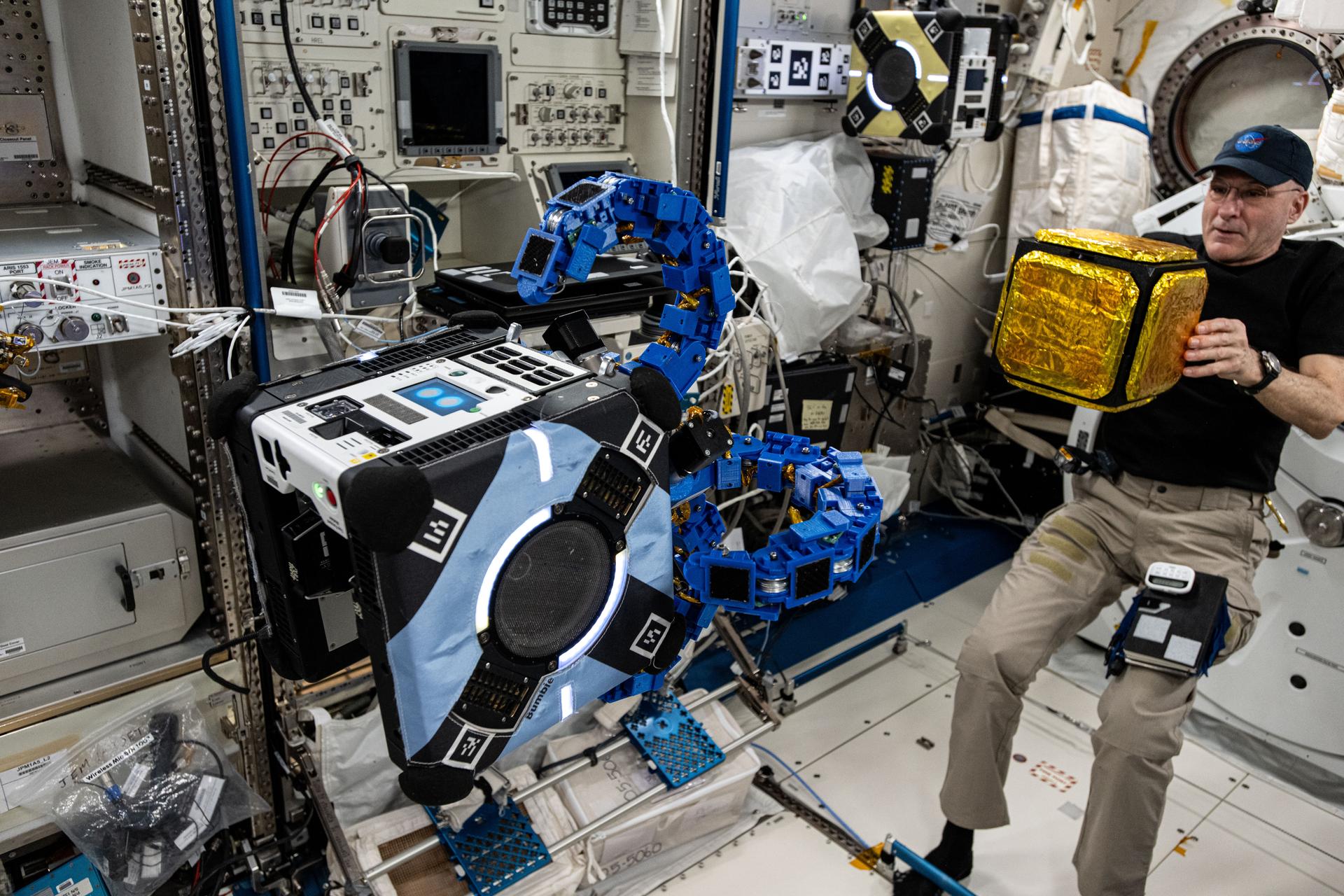 NASA astronaut and Expedition 72 Flight Engineer Don Pettit prepares to deploy a "capture cube" as an Astrobee robotic free-flyer outfitted with tentacle-like grippers prepares to grapple the object inside the International Space Station's Kibo laboratory module.