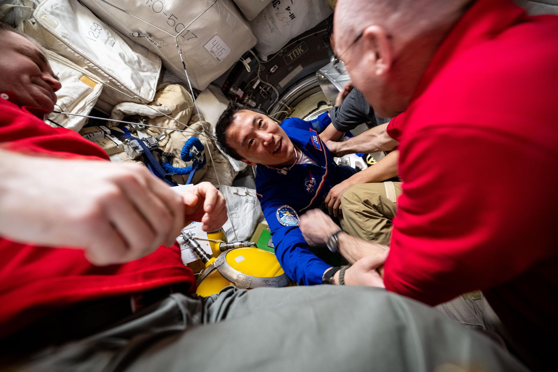 NASA astronaut and Expedition 72 Flight Engineer Jonny Kim enters the International Space Station shortly after docking to the Prichal module aboard the Soyuz MS-27 spacecraft. Kim is greeted by station Commander Alexey Ovchinin of Roscosmos (at left) and flight engineer Don Pettit of NASA (at right).