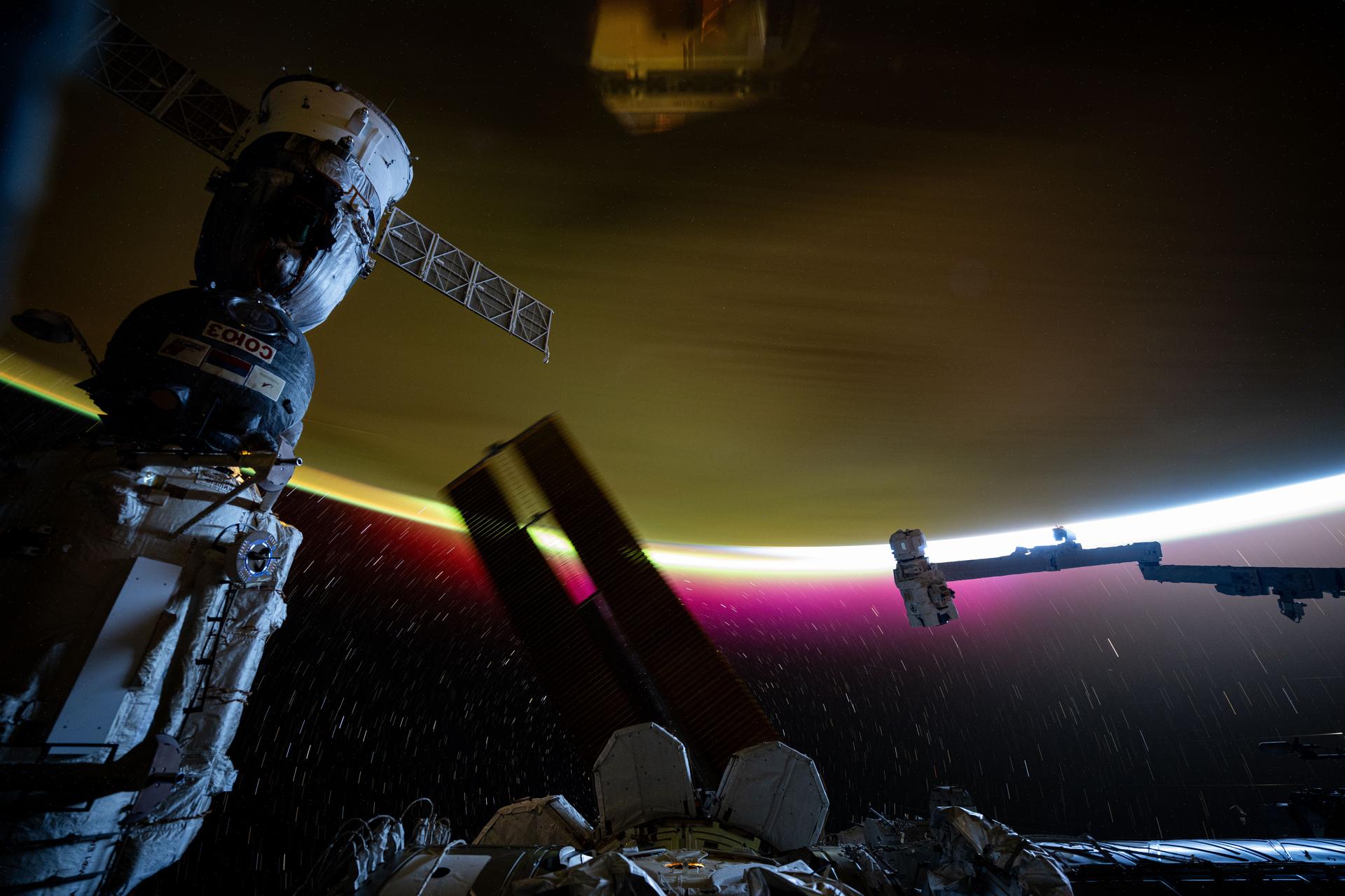 This long duration photograph, taken from the International Space Station as it orbited 271 miles above the South Georgia and the South Sandwich Islands in the southern Atlantic Ocean, highlights star trails and Earth's atmospheric glow moments before the orbital outpost soared into a sunrise. In the foreground (from left), are the Soyuz MS-26 spacecraft docked to the Rassvet module, a set of the station's main solar arrays, and the Canadarm2 robotic arm.