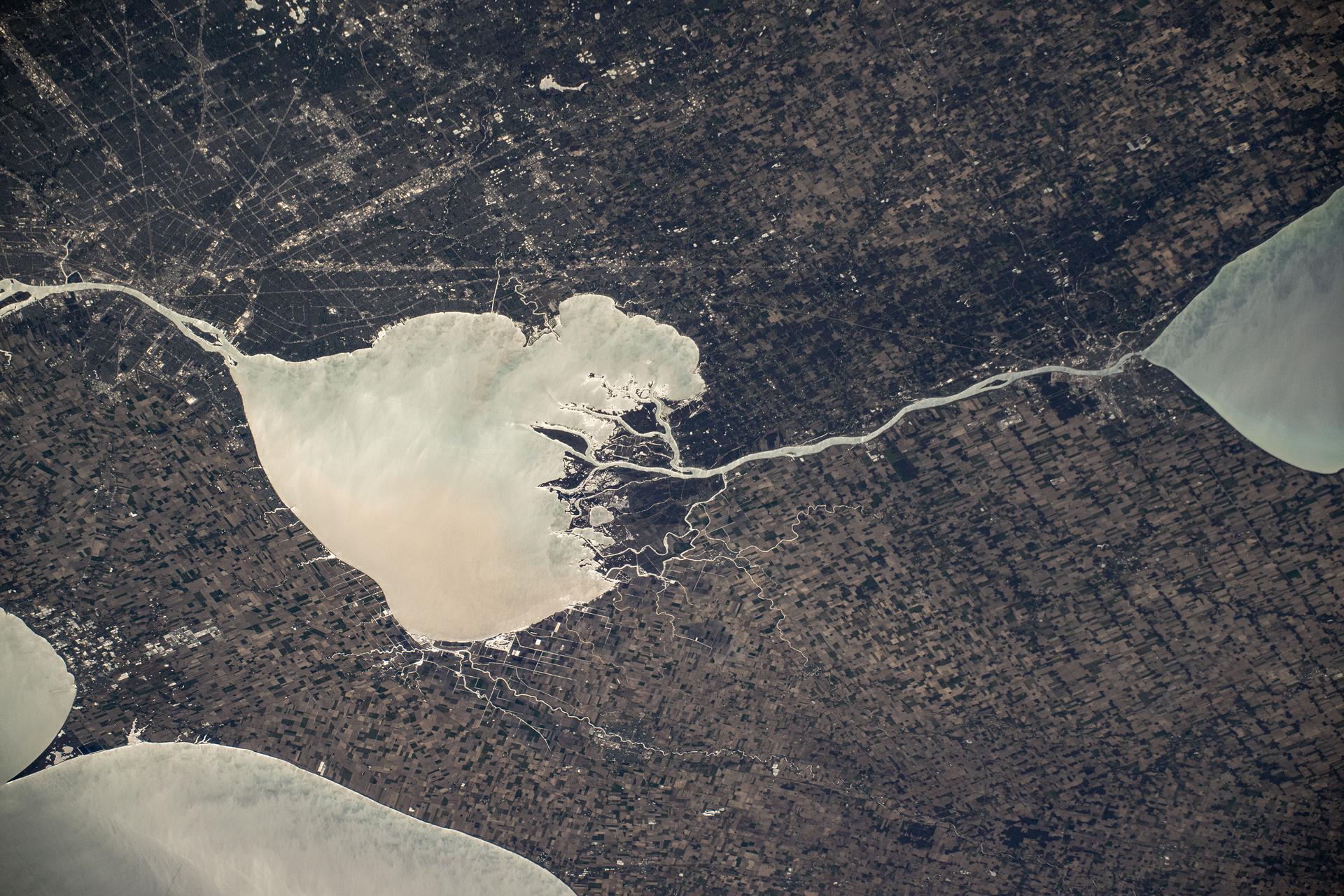 The sun's glint beams off the freshwater Lake St. Clair, sits in between Lake Huron (right) and Lake Erie (bottom left), and separates Detroit, Michigan (top left) from Ontario, Canada, in this photograph from the International Space Station as it orbited 260 miles above.