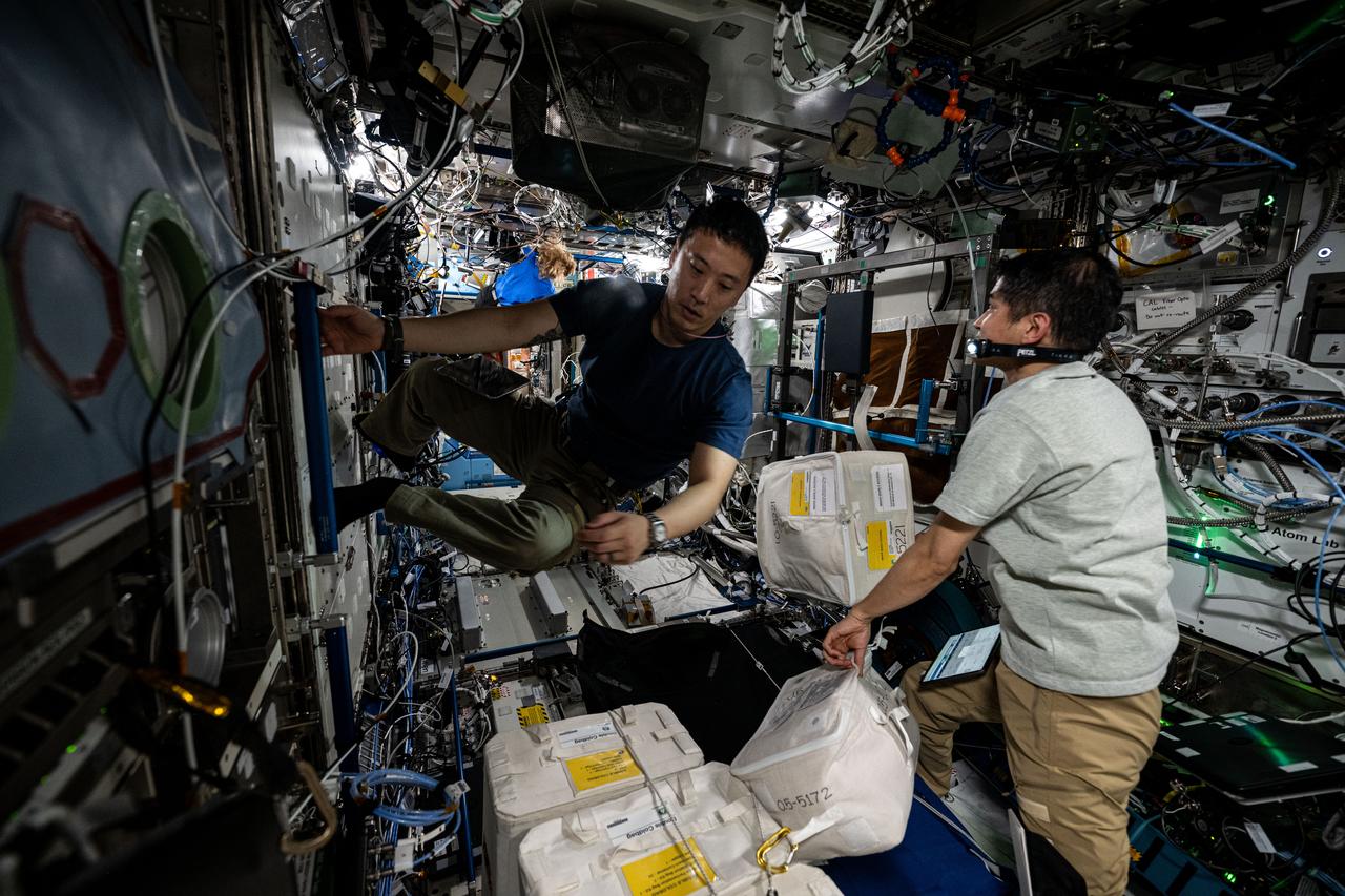 iss073e0001873 (April 22, 2025) --- (From left) Astronauts Jonny Kim of NASA and Takuya Onishi of JAXA (Japan Aerospace Exploration Agency), Expedition 73 Flight Engineer and Commander respectively, work inside the International Space Station's Destiny laboratory module stowing cargo recently delivered aboard the SpaceX Dragon cargo craft.