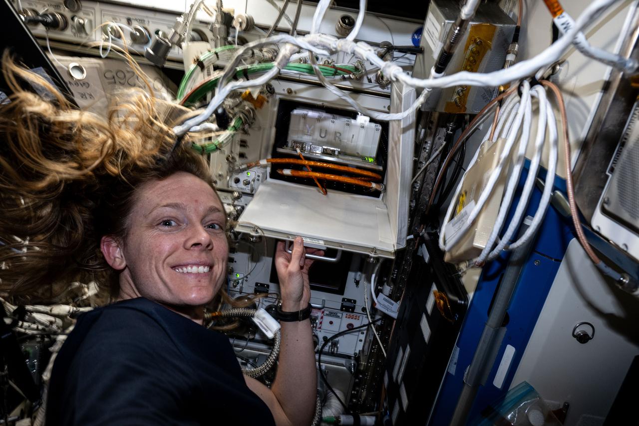 iss073e0002614 (April 28, 2025) --- NASA astronaut and Expedition 73 Flight Engineer Nichole Ayers shows off research hardware inside the International Space Station's Columbus laboratory module. The Space Automated Bioproduct Laboratory is a research incubator that enables biology investigations into the effects of microgravity on cells, microbes, plants, and more.
