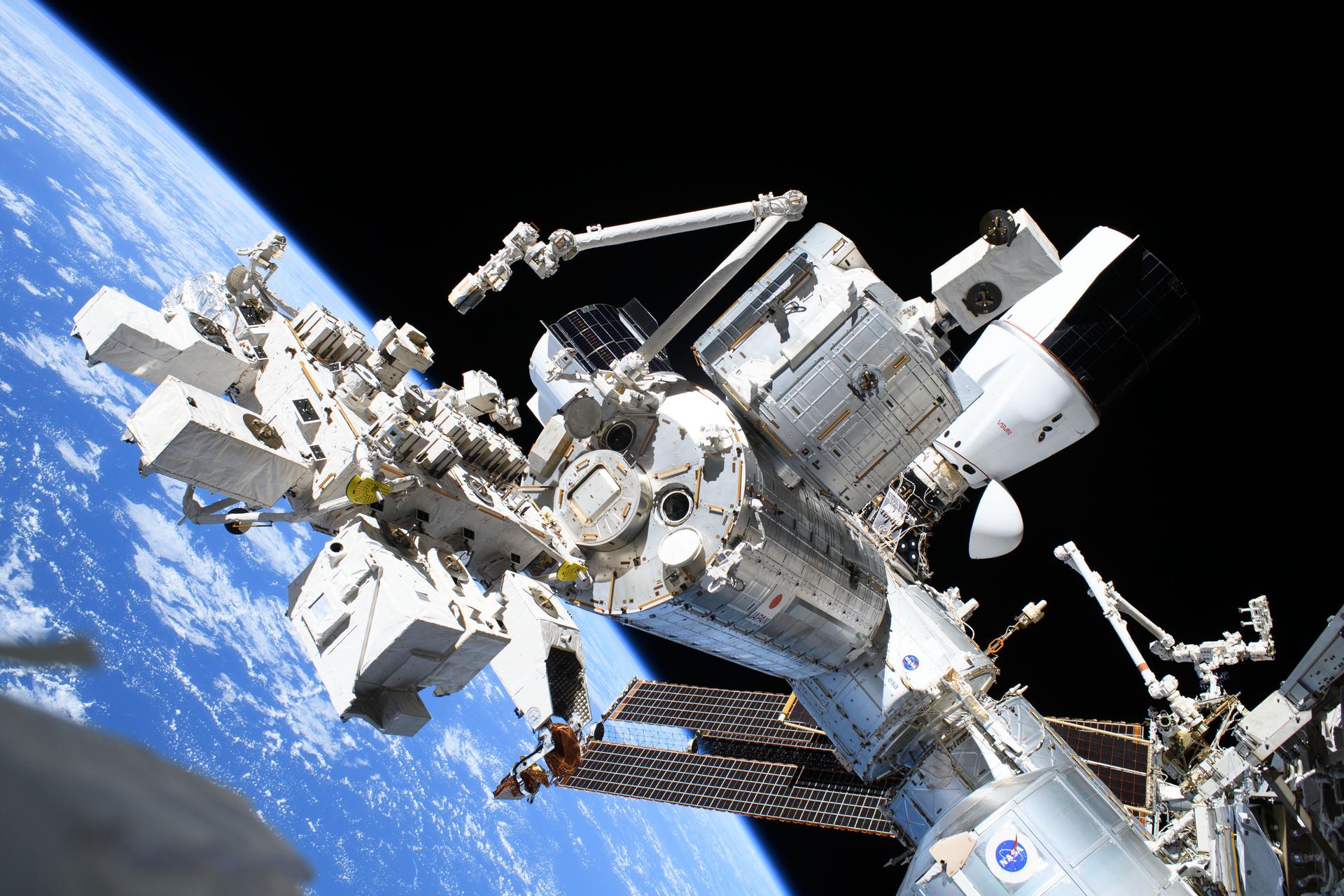 This photograph from NASA spacewalker Nichole Ayers looks to the forward portion of the International Space Station and highlights the Kibo laboratory module with the Japanese robotic arm, the SpaceX Dragon cargo spacecraft docked to the Harmony module's space-facing port, and the partially obscured SpaceX Dragon crew spacecraft docked to Harmony's forward port. The International Space Station was orbiting 260 miles above the Pacific Ocean east of the Hawaiian island chain.