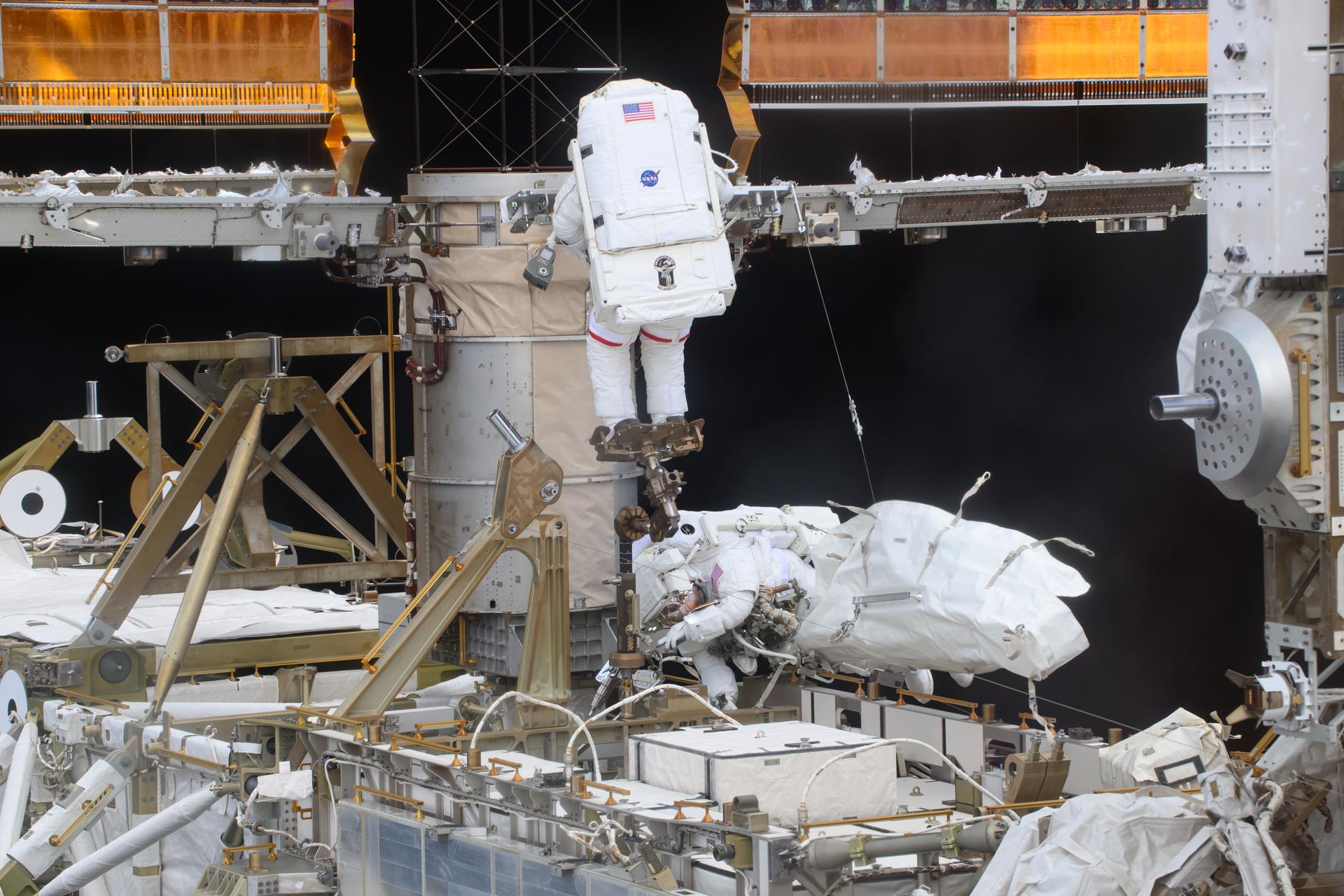NASA astronauts Anne McClain (top) and Nichole Ayers (below), both Expedition 73 flight engineers, are pictured near one of the International Space Station's main solar arrays during a spacewalk to upgrade the orbital outpost's power generation system and relocate a communications antenna.
