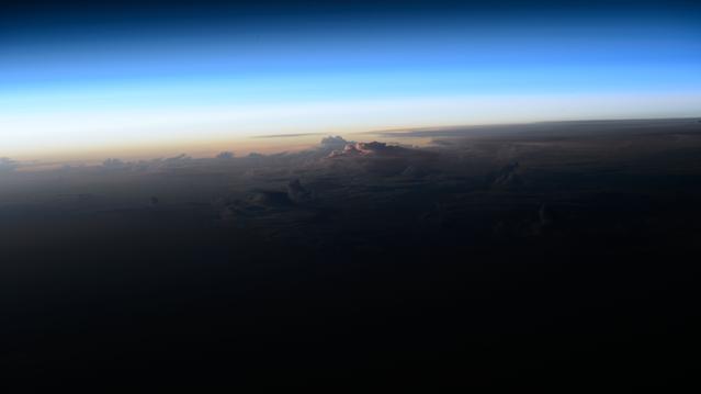 NASA image: An orbital sunrise breaks above the clouds