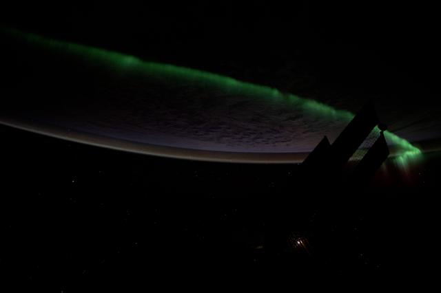 NASA image: An atmospheric glow crowns Earth's horizon as an aurora streams