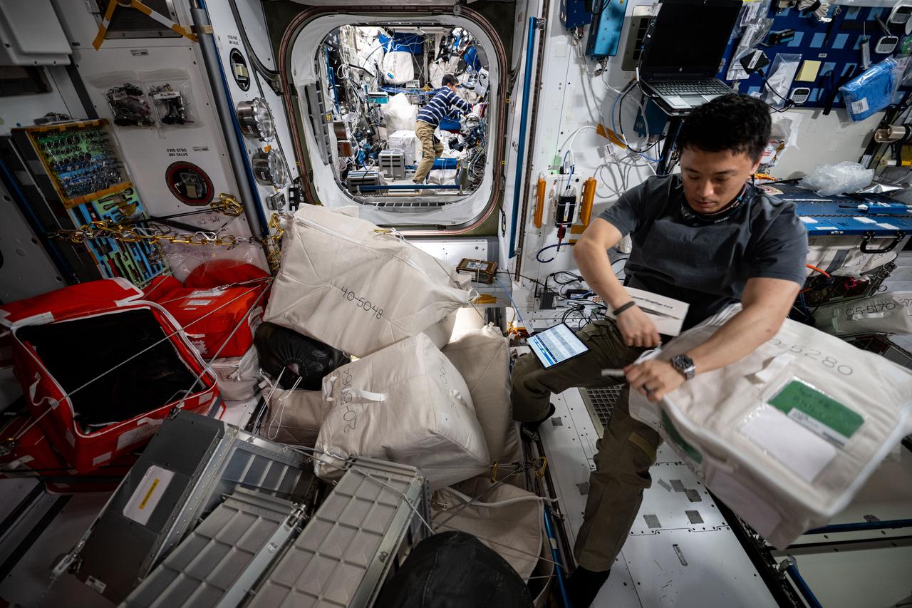 iss073e0071231 (May 14, 2025) --- NASA astronaut and Expedition 73 Flight Engineer Jonny Kim works inside the International Space Station's Harmony module gathering and organizing cargo to be packed inside the SpaceX Dragon cargo spacecraft before its departure. In the rear, station Commander Takuya Onishi from JAXA (Japan Aerospace Exploration Agency) works inside the Columbus laboratory module.