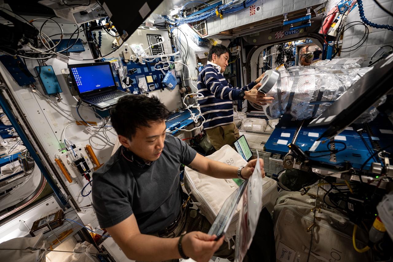 iss073e0071328 (May 14, 2025) --- Astronauts Jonny Kim of NASA and Takuya Onishi of JAXA (Japan Aerospace Exploration Agency), Expedition 73 flight engineer and commander respectively, work inside the International Space Station's Harmony module gathering and organizing cargo to be packed inside the SpaceX Dragon cargo spacecraft before its departure.