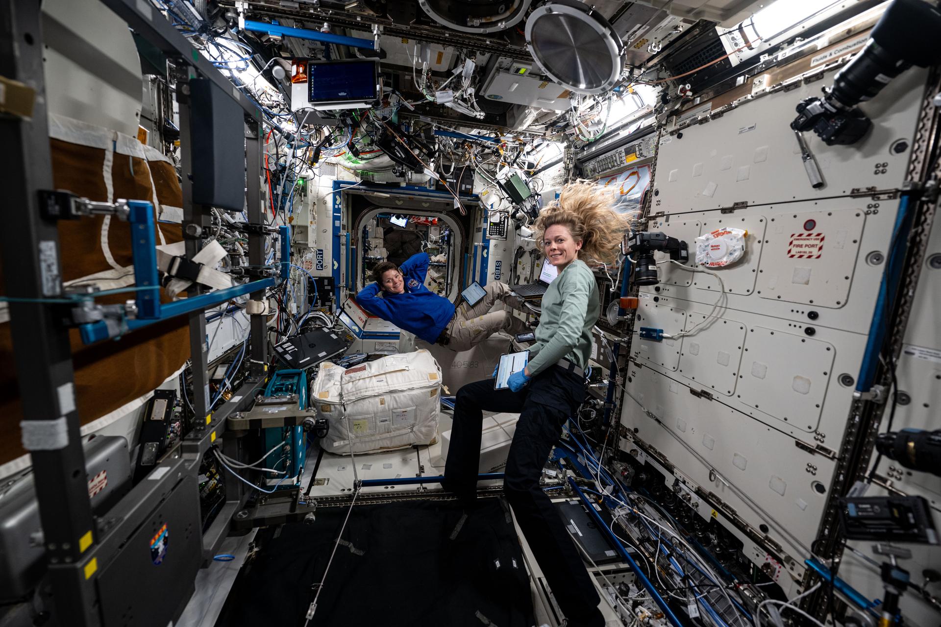 (From left) Expedition 73 Flight Engineers Anne McClain and Nichole Ayers, both NASA astronauts, take a break and pose for a portrait aboard the International Space Station Destiny laboratory module.