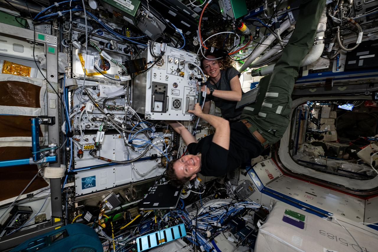 iss073e0071535 (May 16, 2025) --- (From top) Expedition 73 Flight Engineers Nichole Ayers and Anne McClain, both NASA astronauts, pose for a portrait while verifying the functionality and replacing hardware on the Exploration Potable Water Dispenser (xPWD). The xPWD is located in the International Space Station's Destiny laboratory module and is demonstrating advanced water sanitization methods, microbial growth reduction, and a heater to dispense hot water for use aboard the orbital outpost and future spacecraft.