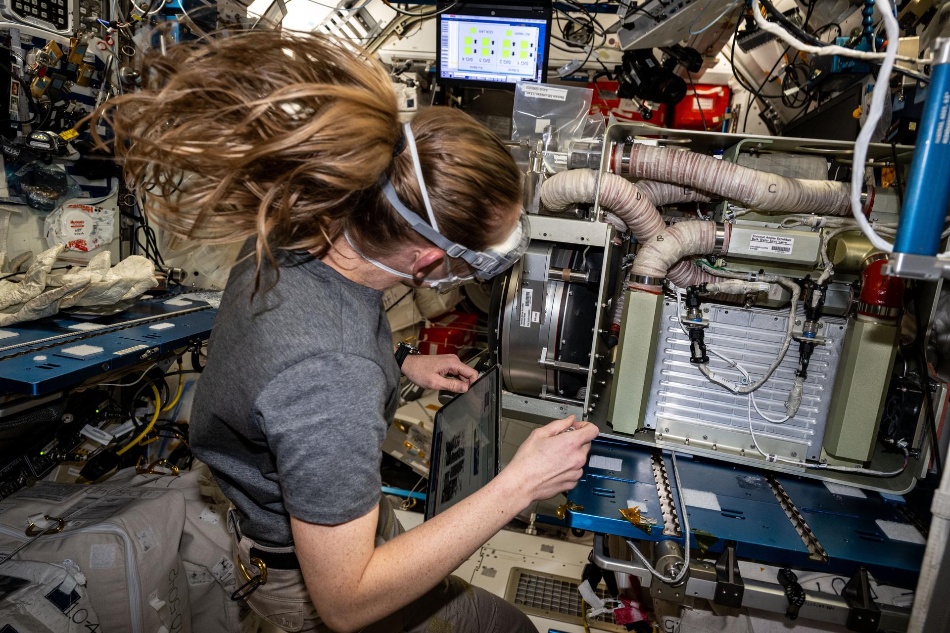 NASA astronaut and Expedition 73 Flight Engineer Nichole Ayers replaces components on an experimental carbon dioxide removal device. Also called the Thermal Amine Scrubber, the advanced life support mechanism is testing a new method that removes carbon dioxide from the station’s atmosphere and recovers water for oxygen generation.