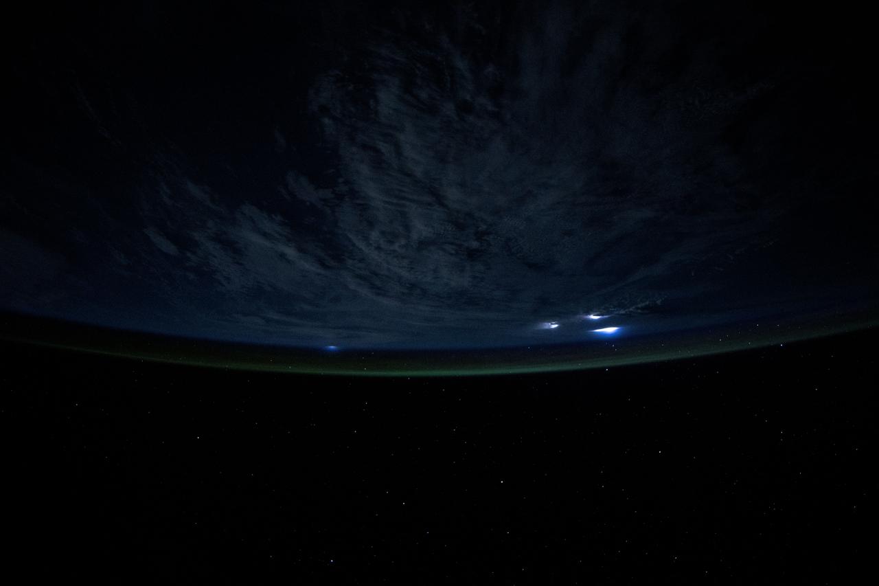 iss073e0111251 (May 18, 2025) --- Lightining illuminates the cloud tops during a storm underneath Earth's atmospheric glow in this photograph from the International Space Station as it orbited 259 miles above the Atlantic Ocean east of the Bahamas.