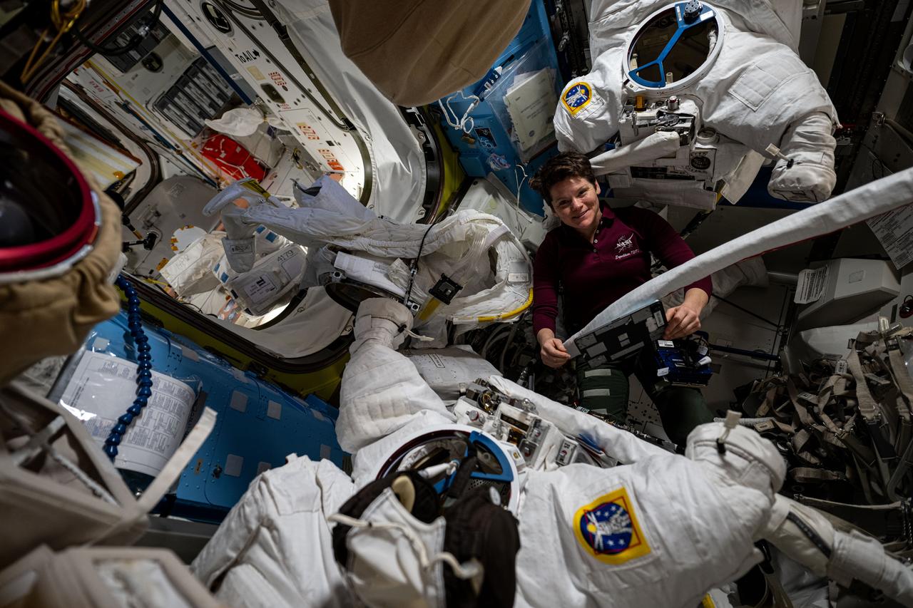 iss073e0118112 (May 29, 2025) --- NASA astronaut and Expedition 73 Flight Engineer Anne McClain checks out a pair of spacesuits during routine maintenance operations inside the International Space Station's Quest airlock.