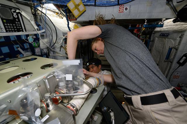 NASA image: Astronauts Takuya Onishi and Nichole Ayers replace components on an experimental carbon dioxide removal device