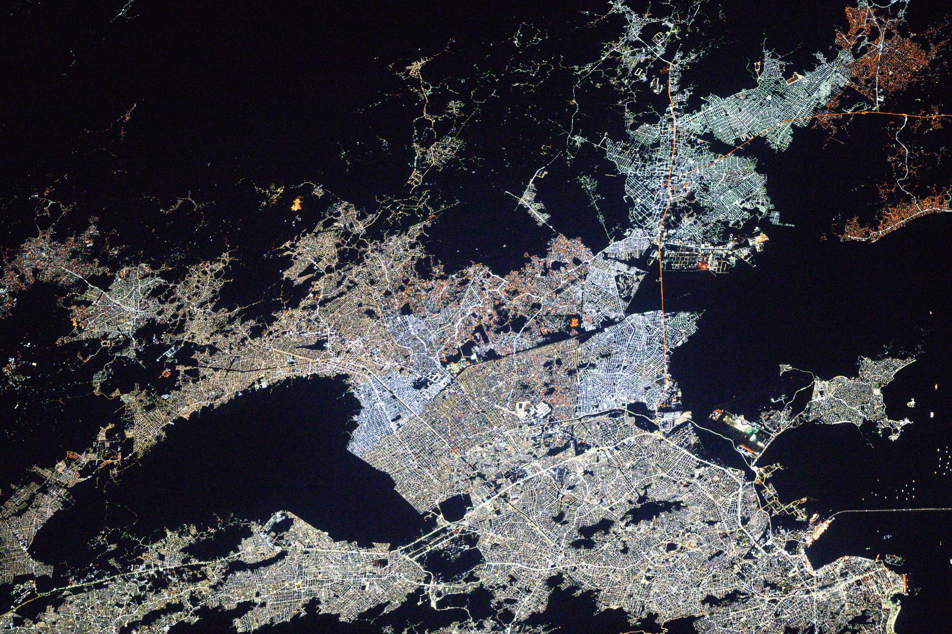 Rio de Janiero, Brazil's capital and second most-populous city, along with its surrounding suburbs, is pictured in between the dark voids representing Nova Iguaçu Volcano (left) and Guanabara Bay (right) at approximately 3:06 a.m. local time from the International Space Station as it orbited 264 miles above the Atlantic Ocean.