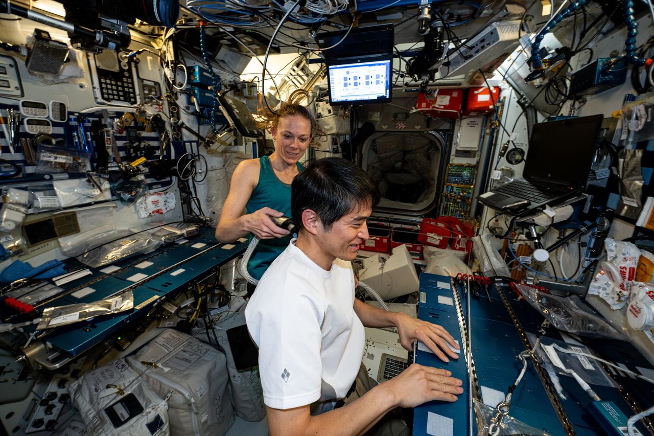 iss073e0120070 (May 31, 2025) --- Astronauts Takuya Onishi of JAXA (Japan Aerospace Exploration Agency) and Nichole Ayers of NASA, Expedition 73 Commander and Flight Engineer respectively, are pictured inside the International Space Station's Harmony module. Ayers trims Onishi's hair using an electric razor with a suction hose attached that collects loose hairs to protect the station's atmosphere.