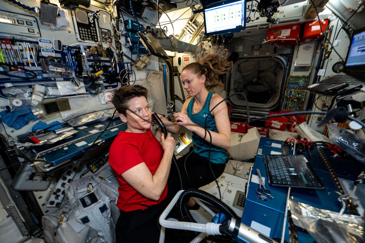 iss073e0120086 (May 31, 2025) --- NASA astronauts (left to right) Anne McClain and Nichole Ayers, both Expedition 73 Flight Engineers, are pictured inside the International Space Station's Harmony module. Ayers trims McClain's hair as a suction hose collects loose hairs to protect the station's atmosphere.