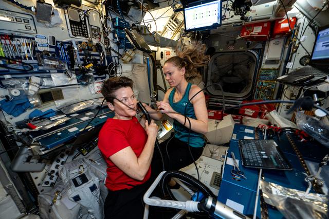 NASA image: Astronaut Nichole Ayers trims Astronaut Anne McClain's hair