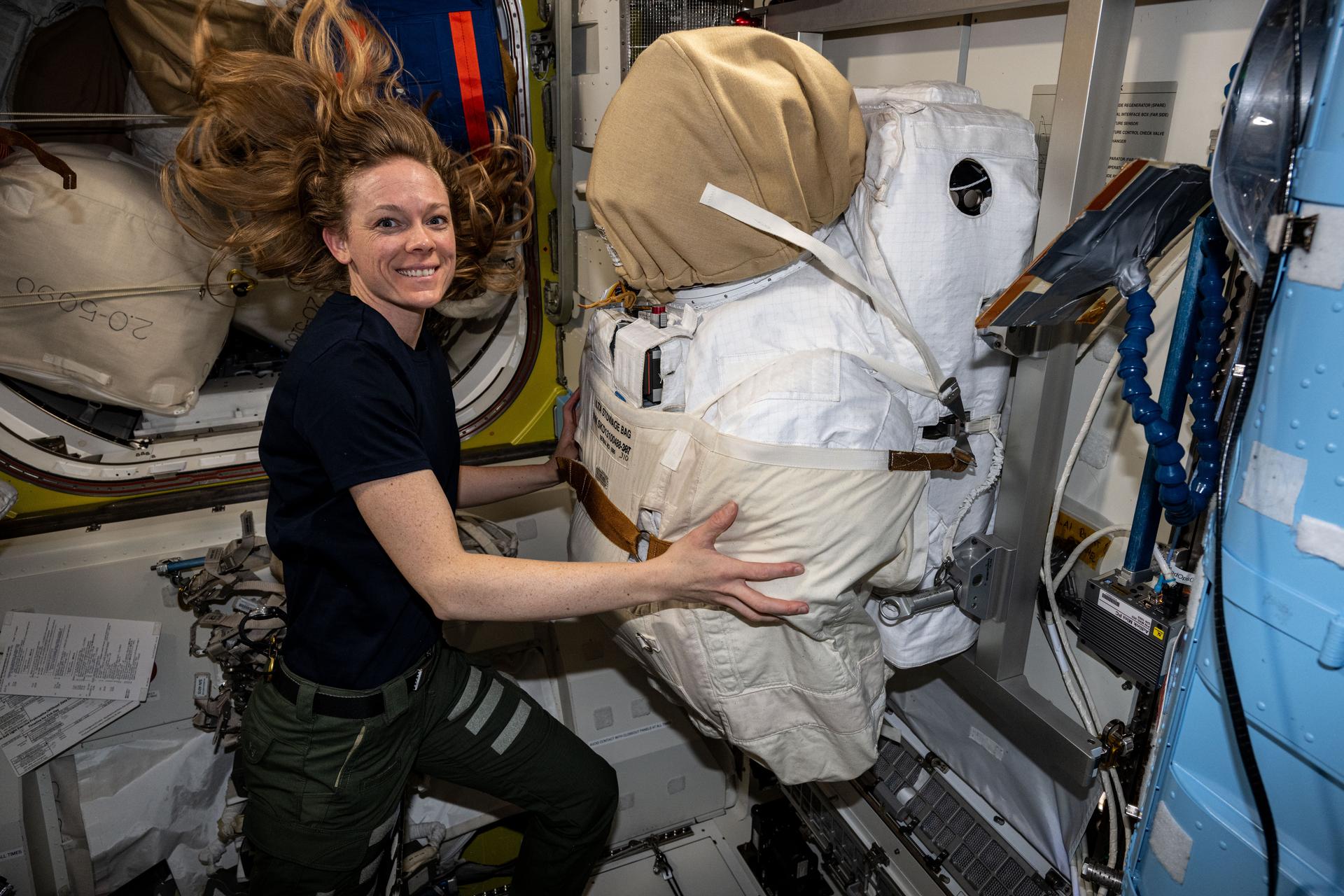 NASA astronaut and Expedition 73 Flight Engineer Nichole Ayers checks out a spacesuit stowed inside the International Space Station's Quest airlock.