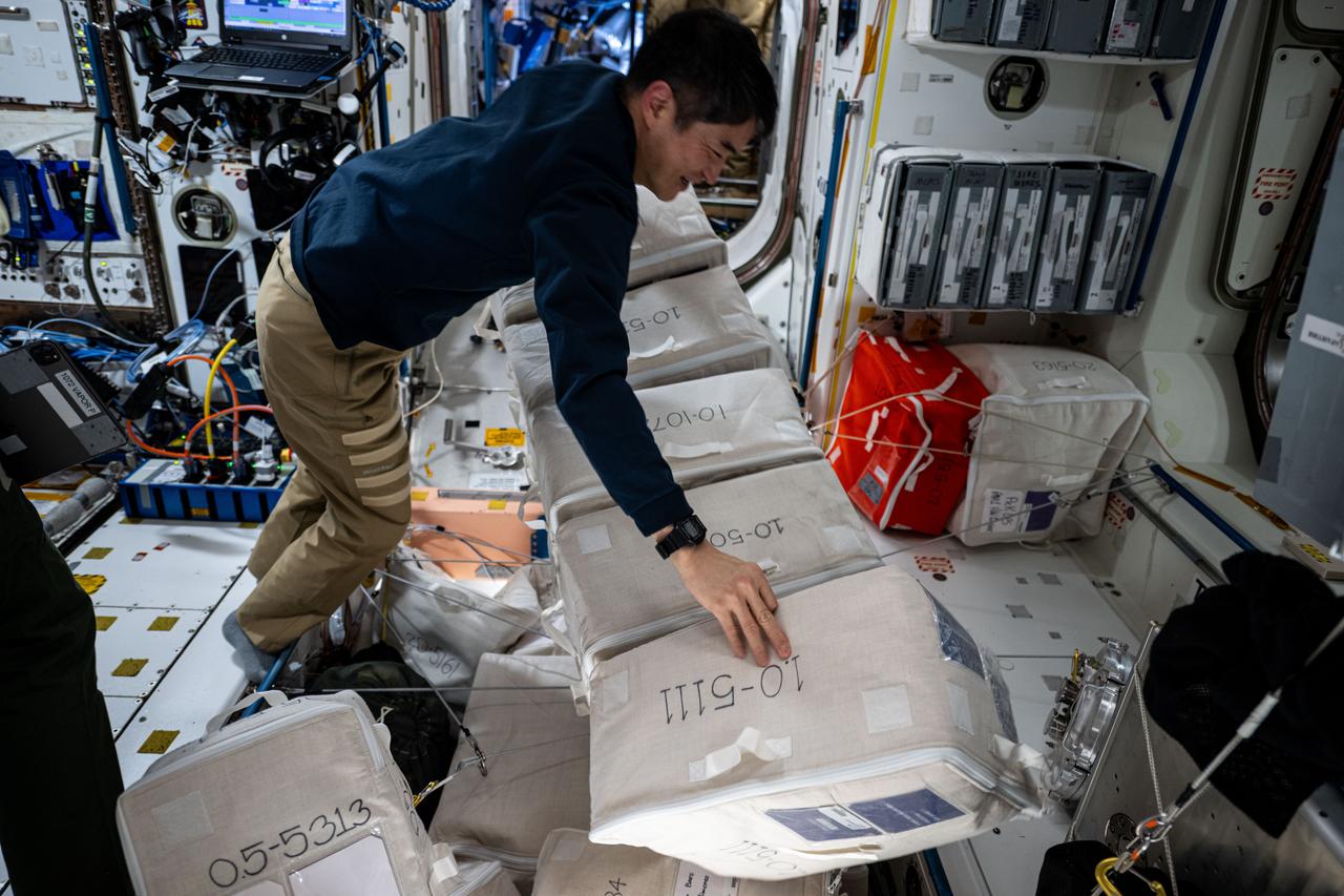 iss073e0221788 (June 19, 2025) --- JAXA (Japan Aerospace Exploration Agency) astronaut and Expedition 73 Commander Takuya Onishi organizes cargo bags inside the International Space Station's Unity module.