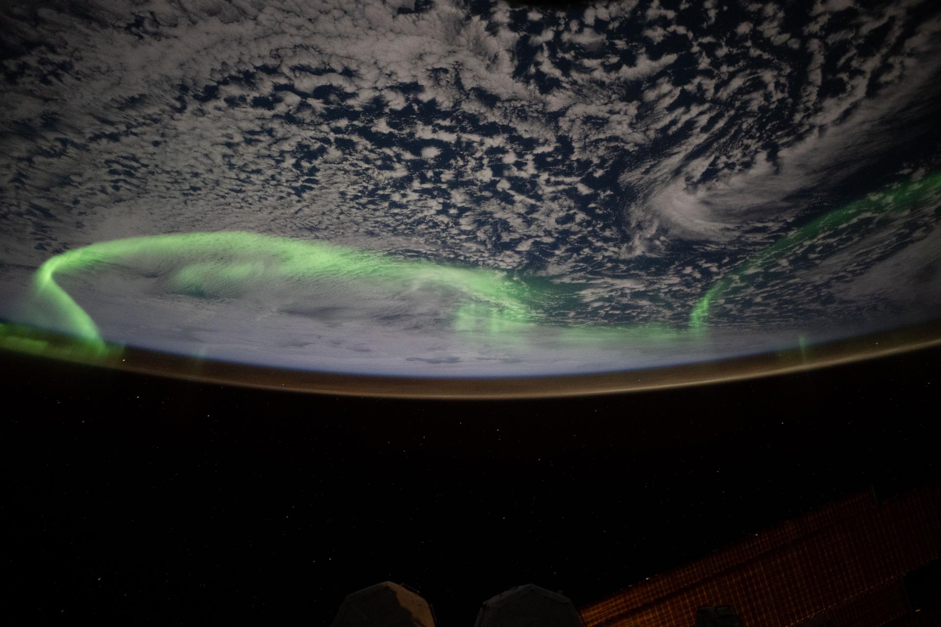 The aurora australis arcs above a partly cloudy Indian Ocean in this photograph from the International Space Station as it orbited 269 miles above in between Australia and Antarctica.