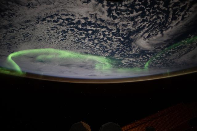 NASA image: The aurora australis arcs above a partly cloudy Indian Ocean