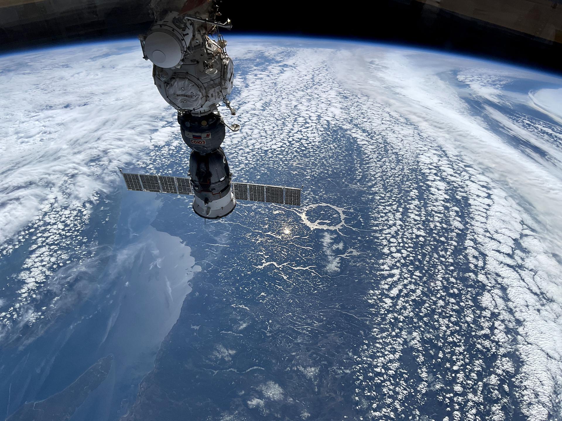 The Soyuz MS-27 spacecraft is pictured docked to the International Space Station's Prichal module while soaring 263 miles above the Canadian province of Quebec. Prominently featured in the center of this photograph is the 214 million-year-old Manicouagan crater.