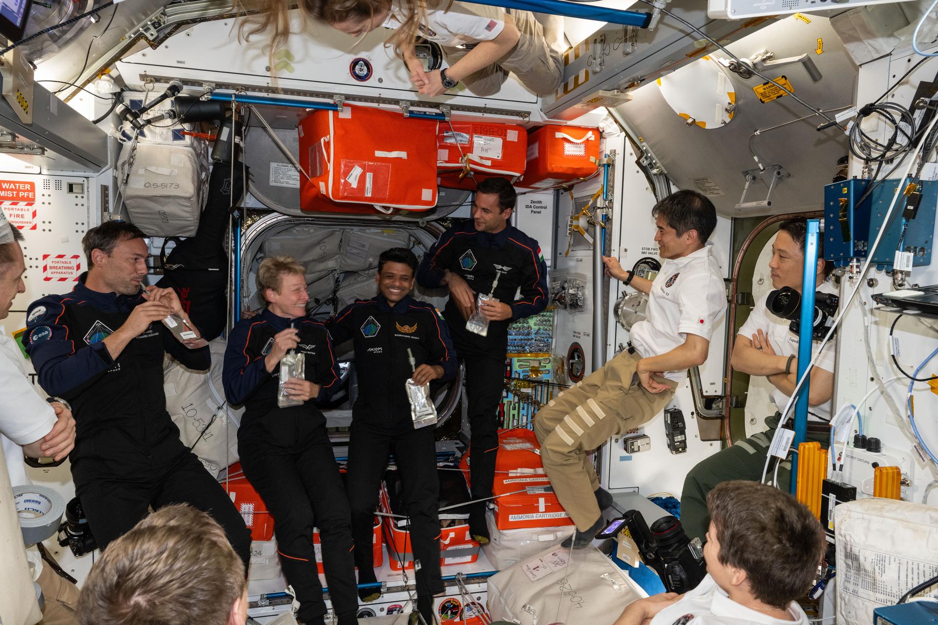 The Axiom Mission 4 private astronauts gather with drink pouches inside the International Space Station shortly after docking to the orbital outpost's space-facing port on the Harmony module. In the dark suits (from left) are, Ax-4 crewmates Sławosz Uznański-Wiśniewski, Peggy Whitson, Shubhanshu Shukla, and Tibor Kapu. Surrounding the Ax-4 crew (clockwise from top are) Expedition 73 crewmates Nichole Ayers, Takuya Onishi, Jonny Kim, Anne McClain, Kirill Peskov, and Sergey Ryzhikov.