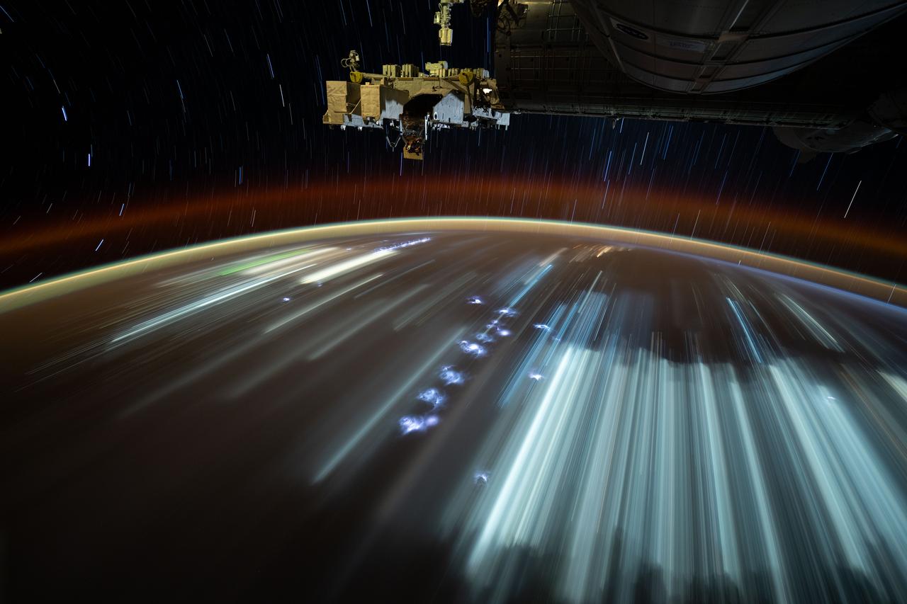 iss073e0251575 (June 20, 2025) --- This long-duration photograph was taken from the International Space Station orbiting 260 miles above the Indian Ocean off the coast of the Indonesian island of Java. City lights and lightning storms streak below star trails above Earth's atmopsheric glow.
