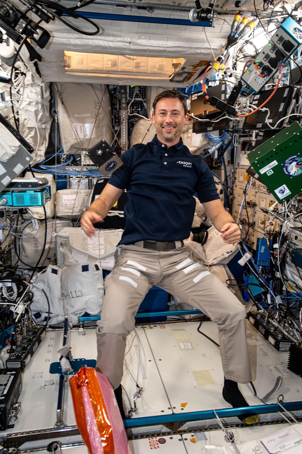 ESA (European Space Agency) astronaut and Axiom Mission 4 Mission Specialist Sławosz Uznański-Wiśniewski shows off research hardware inside the International Space Station's Columbus laboratory module. The large box on the right is supporting a biotechnology study that looks at microalgae as a sustainable source for oxygen in spacecraft life support systems. The smaller box on the left provides a platform to test data processing and algorithms in microgravity.