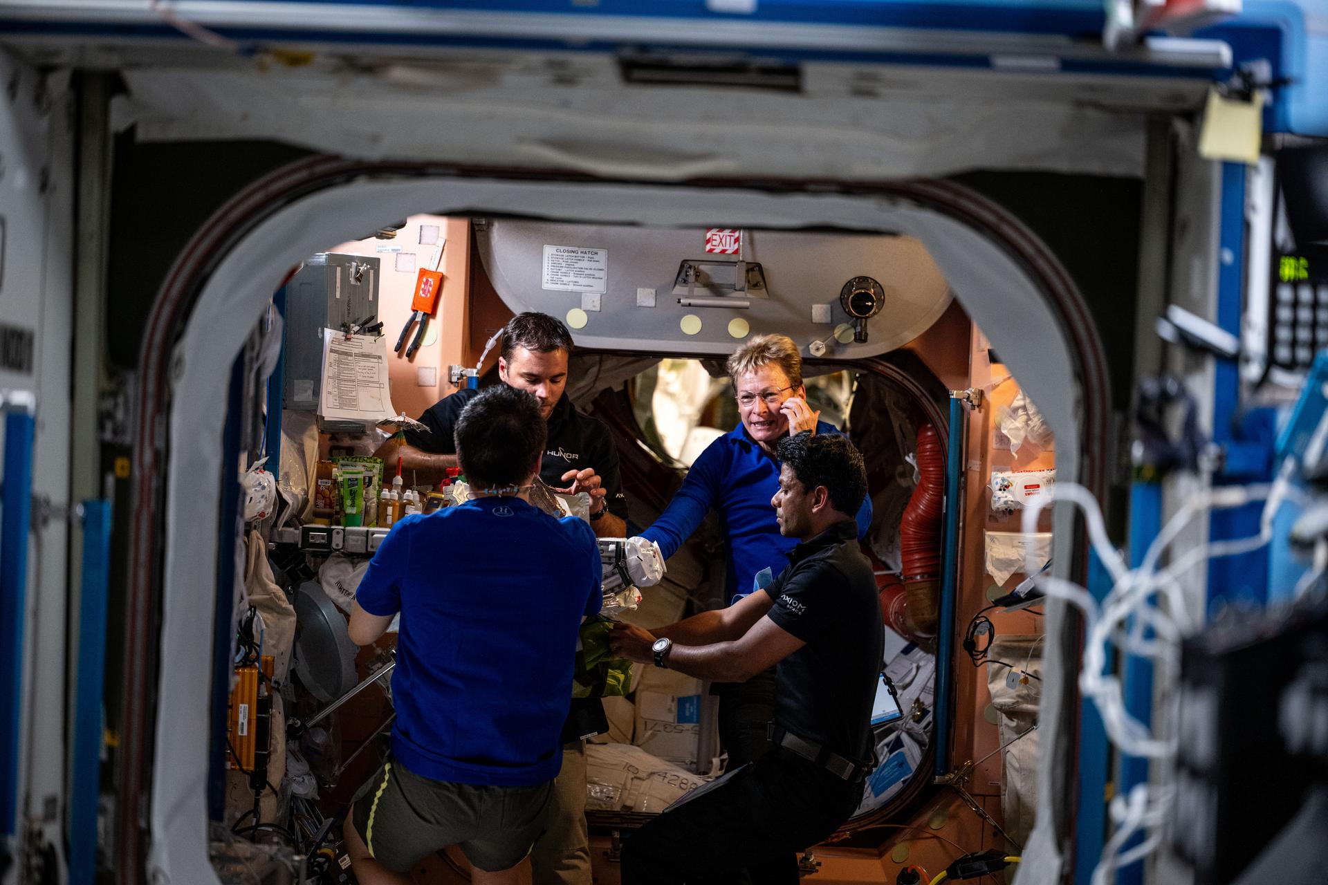 NASA astronaut and Expedition 73 Flight Engineer Jonny Kim (back to camera) joins Axiom Mission 4 crew members (clockwise from top left) Tibor Kapu from Hungary, Peggy Whitson from the U.S., and Shubhanshu Shukla from India for lunch inside the galley of the International Space Station's Unity module.