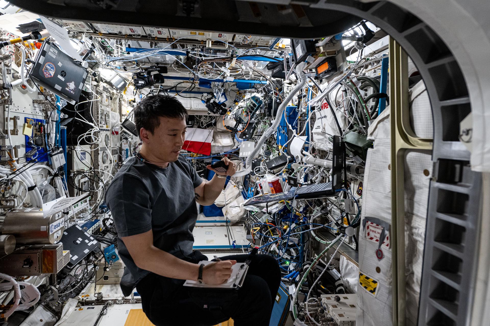ASA astronaut and Expedition 73 Flight Engineer Jonny Kim conducts a ham radio session and takes notes inside the International Space Station's Columbus laboratory module.