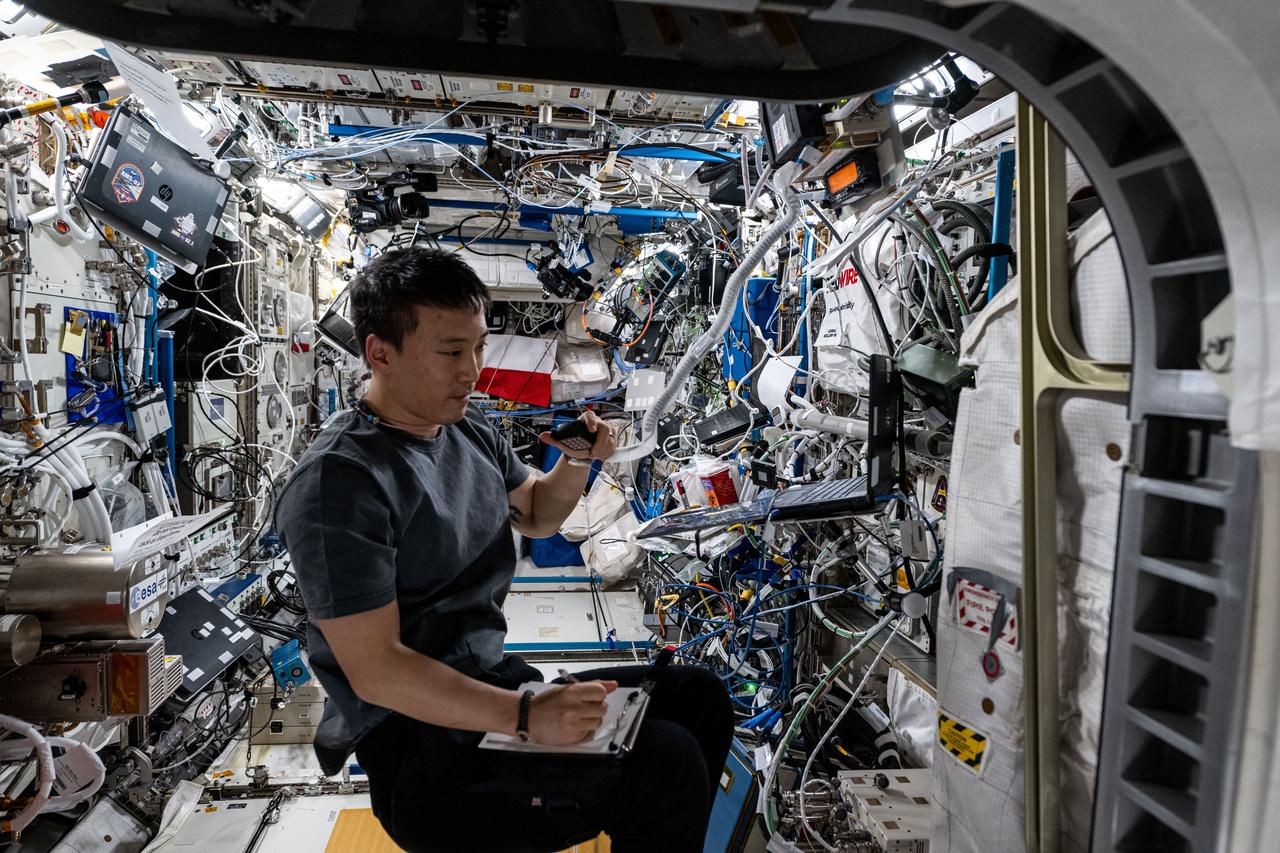 iss073e0252501 (June 29, 2025) --- NASA astronaut and Expedition 73 Flight Engineer Jonny Kim conducts a ham radio session and takes notes inside the International Space Station's Columbus laboratory module.
