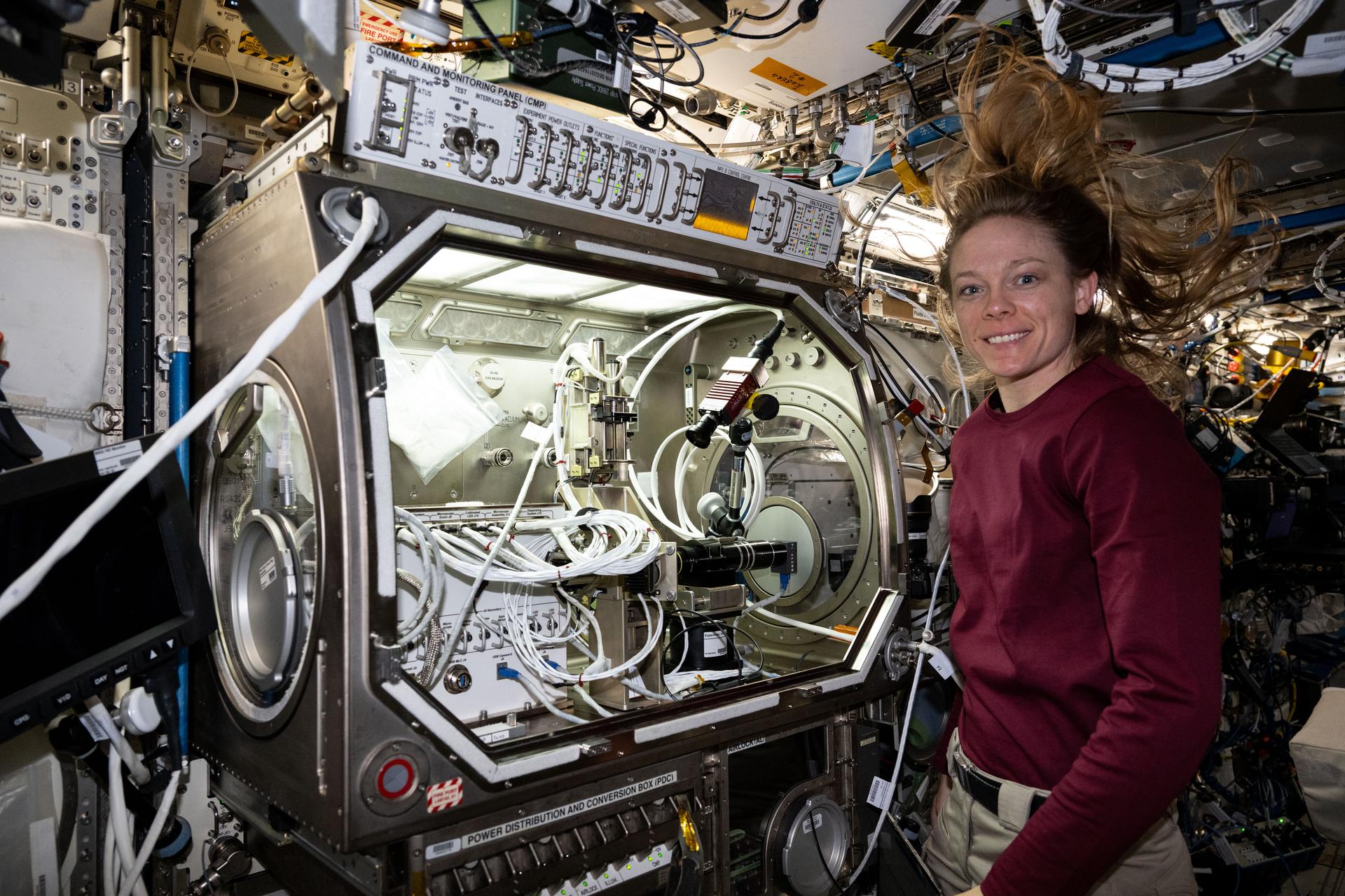 NASA astronaut and Expedition 73 Flight Engineer Nichole Ayers poses for a portrait as she removes physics research hardware from inside the Microgravity Science Glovebox located inside the International Space Station's Destiny laboratory module. Ayers was completing operations with the Ring Sheared Drop investigation that may benefit pharmaceutical manufacturing techniques and 3D printing in space.