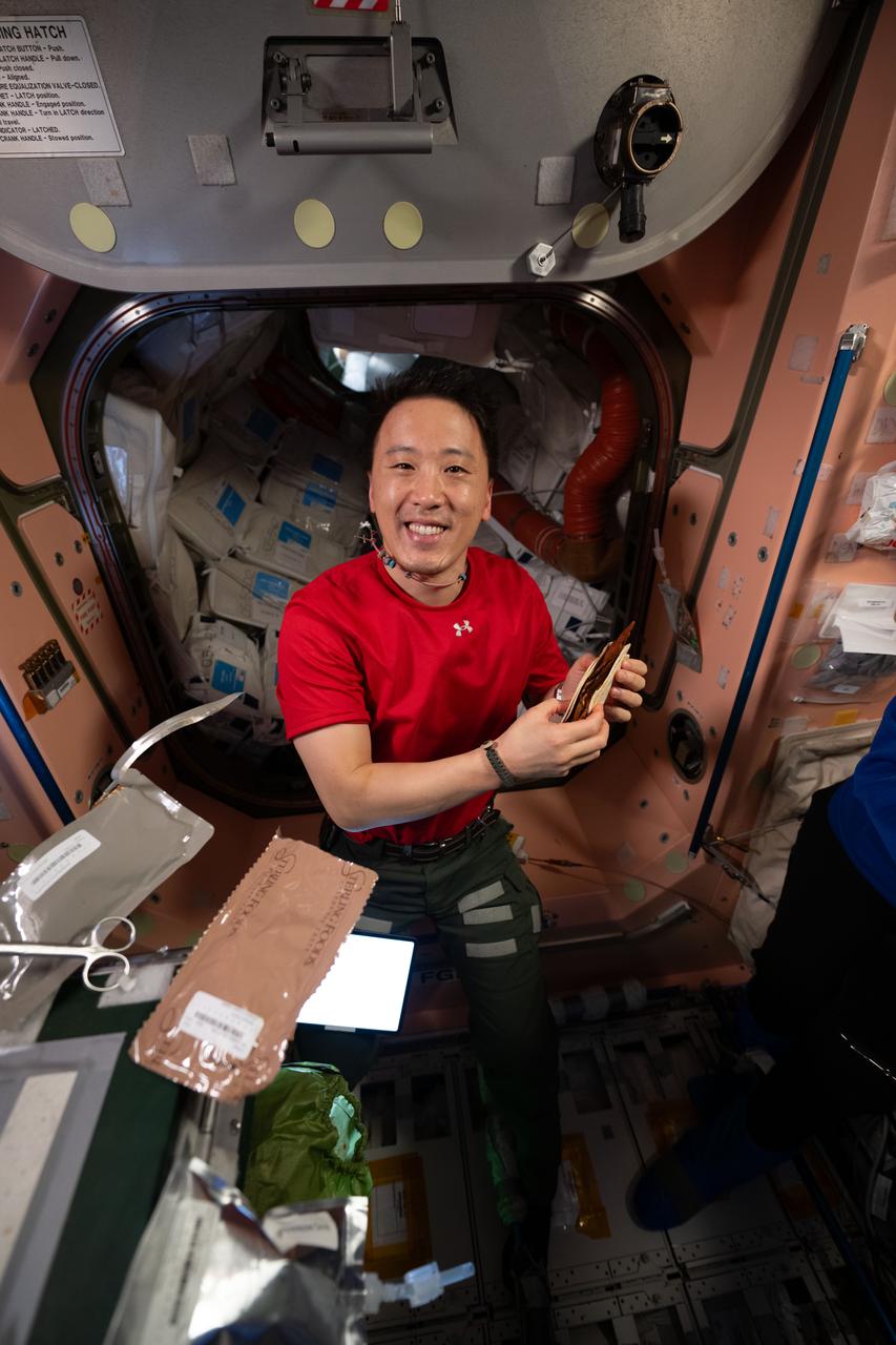 iss073e0254613 (June 20, 2025) --- NASA astronaut and Expedition 73 Flight Engineer Jonny Kim shows off a barbeque brisket taco during dinner time at the galley inside the International Space Station's Unity module.