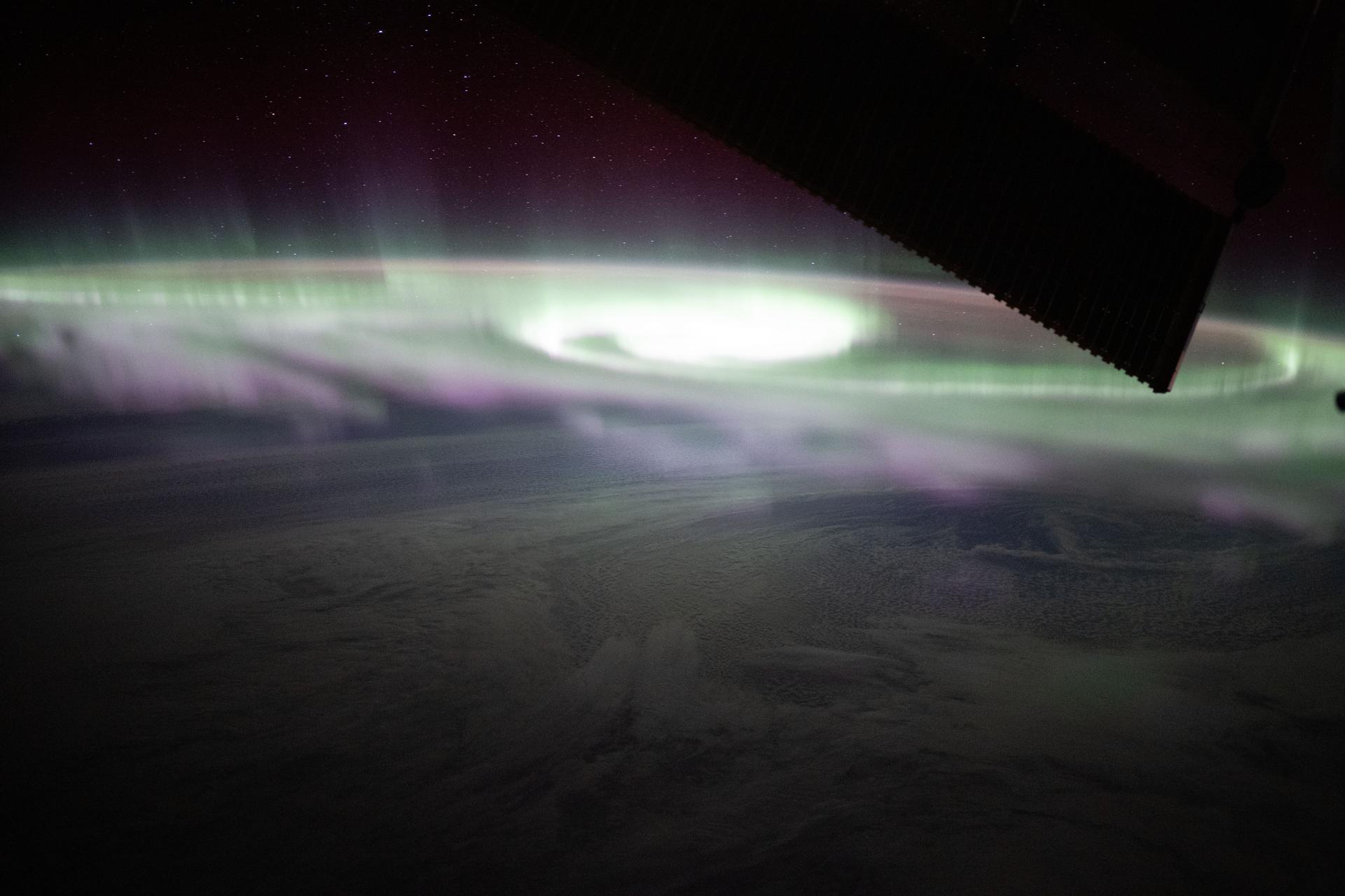 The aurora australis swirls over a cloudy Pacific Ocean in this photograph from the International Space Station as it orbited 270 miles above and southeast of New Zealand.