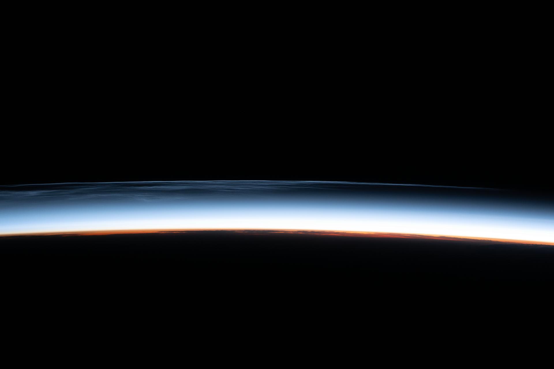 Noctilucent clouds, upper atmospheric clouds illuminated by the sun below Earth's horizon and composed of water vapor crystals that form about 50 miles in altitude during the summertime, are pictured from the International Space Station as it orbited 261 miles above the North Pacific Ocean.