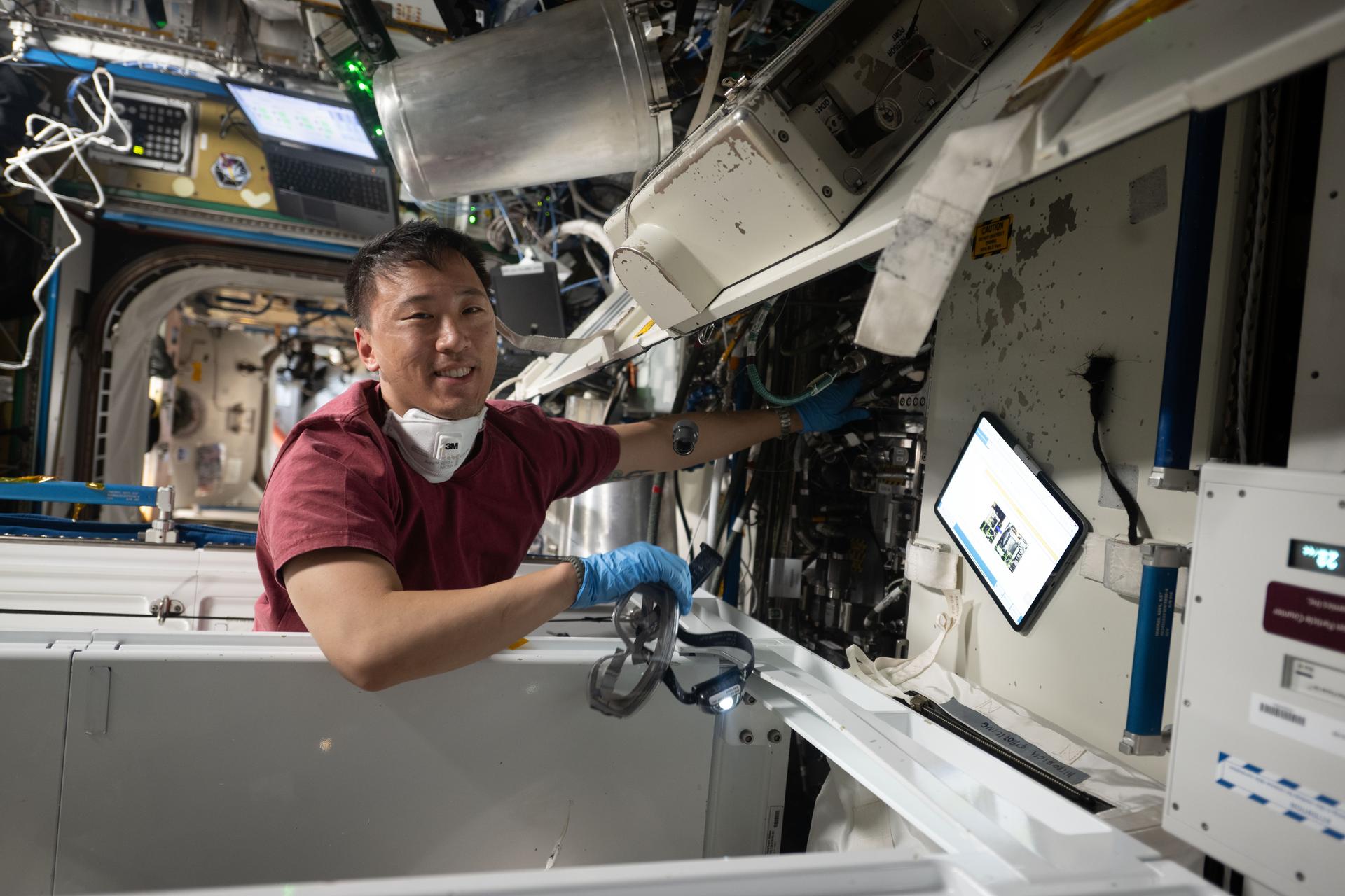 NASA astronaut and Expedition 73 Flight Engineer Jonny Kim works on orbital plumbing tasks inside the International Space Station's Tranquility module where the orbital outpost's restroom, or Waste and Hygiene Compartment, is located.