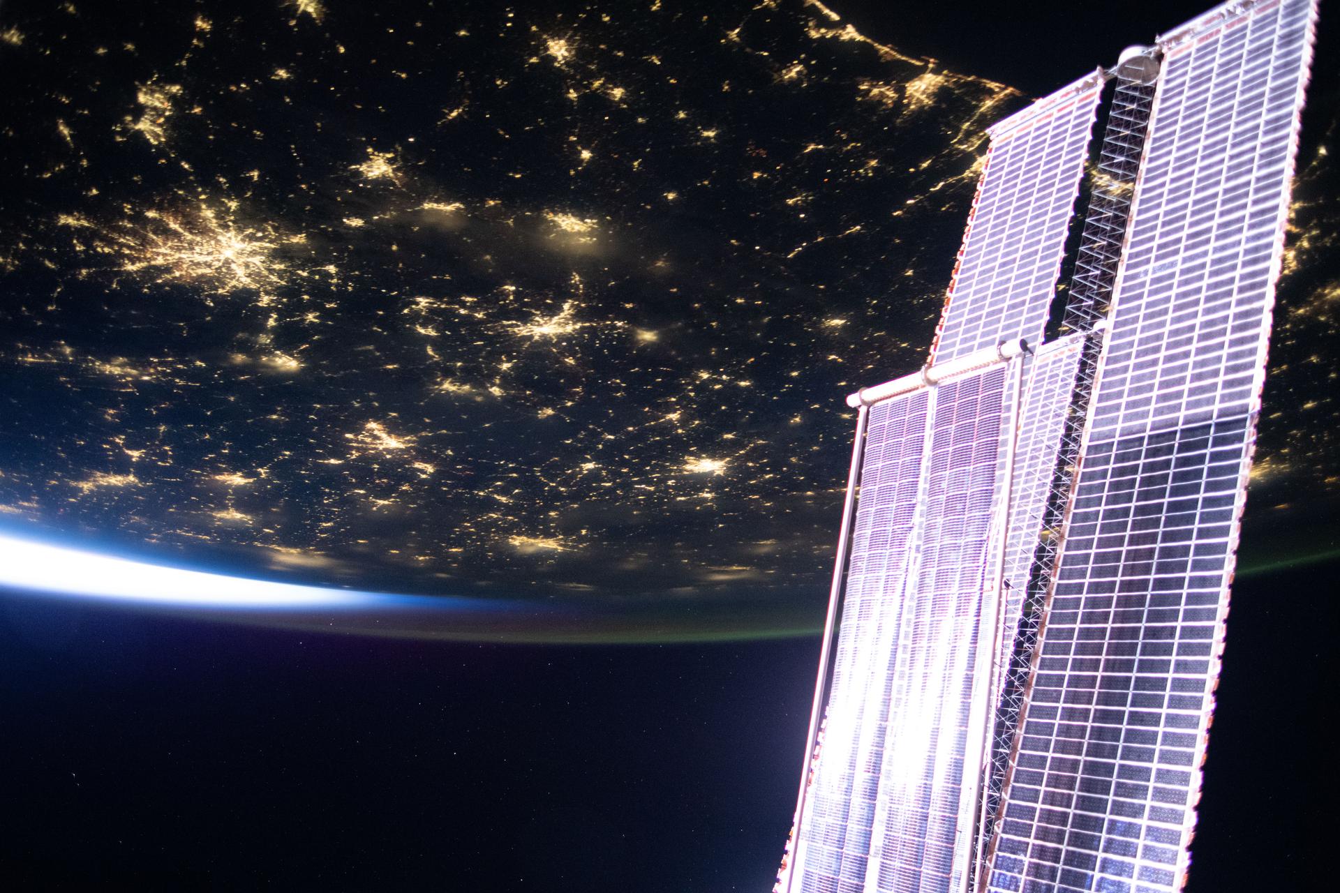 City lights sparkle across the southern United States in this photograph taken at approximately 4:44 a.m. local time from the International Space Station is it orbited into a sunrise 260 miles above Florida. In the right foreground, is a set of the orbital outpost's main solar arrays augmented by a smaller set of roll out solar arrays.
