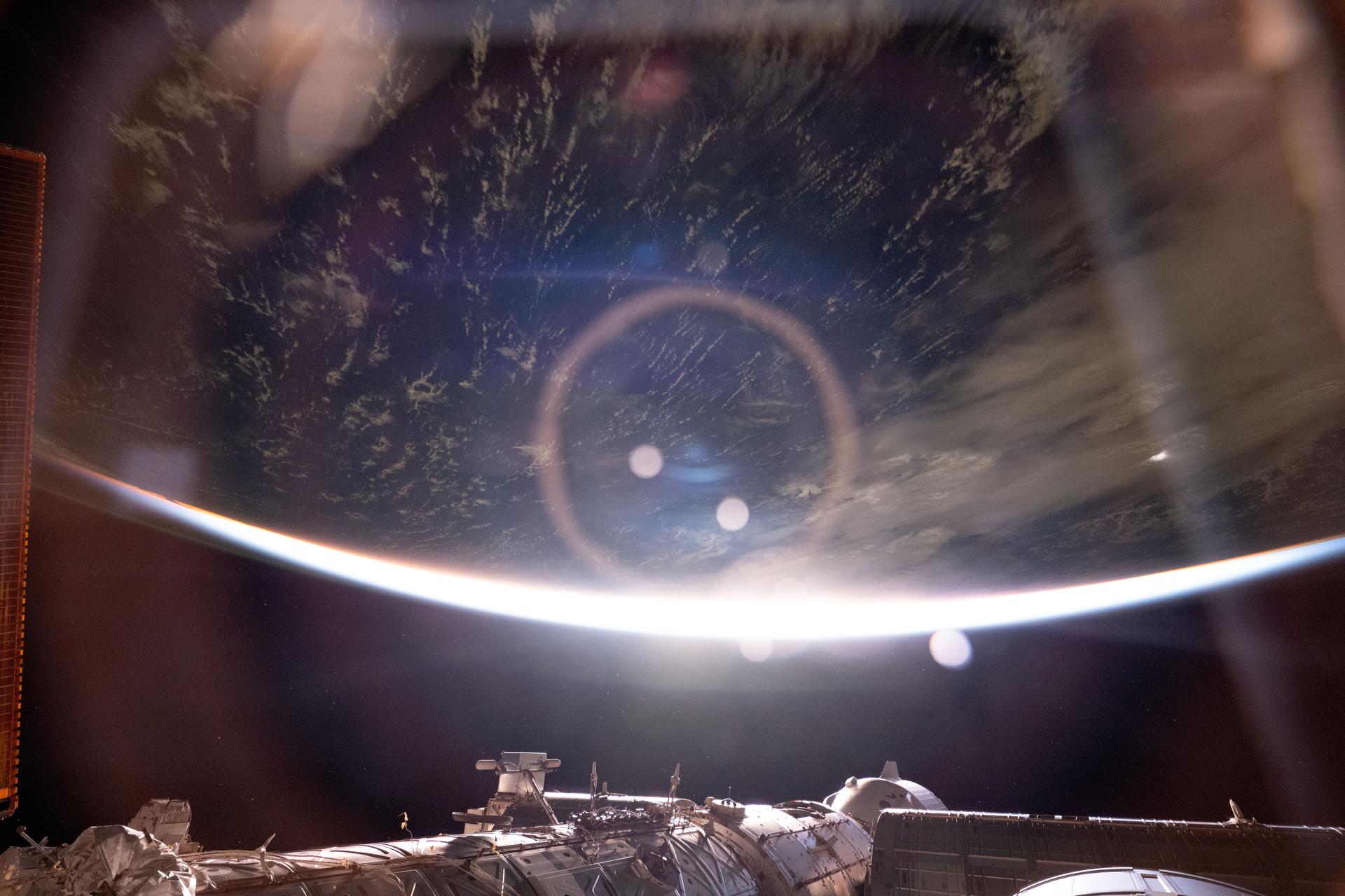 The light from an orbital sunrise refracts through a window inside the International Space Station's "window to the world," the cupola. At bottom, a portion of the orbital outpost's U.S. segment is illuminated including the SpaceX Dragon crew spacecraft docked to the Harmony module's forward port. The station was soaring 259 miles above the Republic of Kiribati in the Pacific Ocean at approximately 3:40 a.m. local time when this photograph was taken.