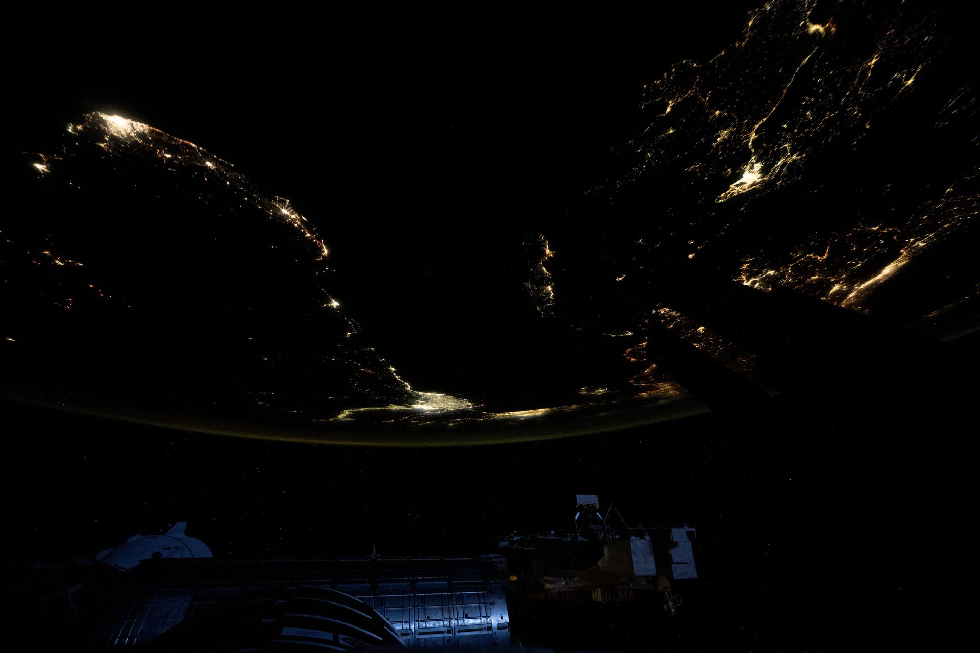 At top left, the city lights of Benghazi, Libya, arc downward toward the glow of civilization on Egypt's Nile Delta outlining Africa's Mediterranean Sea coast. Israel's metropolitan lights then round north and east into Istanbul, Turkey (far right), and Athens, Greece, and their surrounding suburbs in southern Europe. Resting in the center of the Mediterranean's darkness is the Greek island of Crete.