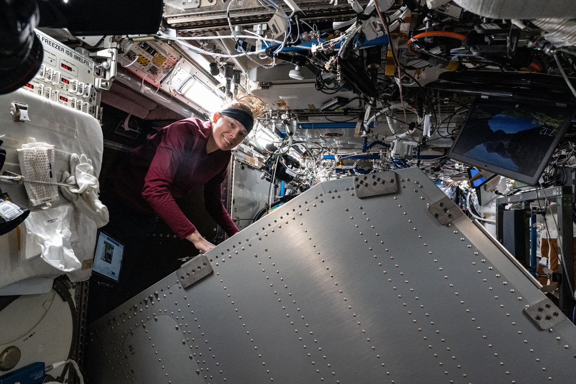 NASA astronaut and Expedition 73 Flight Engineer Nichole Ayers works inside the International Space Station's Destiny laboratory module and cleans components behind the Microgravity Science Glovebox.