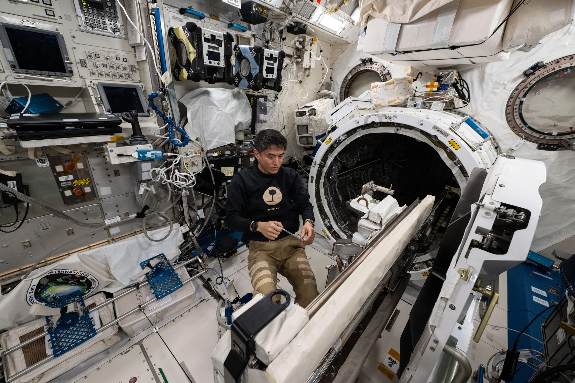 JAXA (Japan Aerospace Exploration Agency) astronaut and Expedition 73 Commander Takuya Onishi removes research hardware attached to the Kibo laboratory module's airlock slide table aboard the International Space Station. The slide table can be retracted back and forth into the airlock where the Japanese robotic arm can grapple a variety of payloads and hardware for installation on the outside of Kibo for exposure to the external space environment.