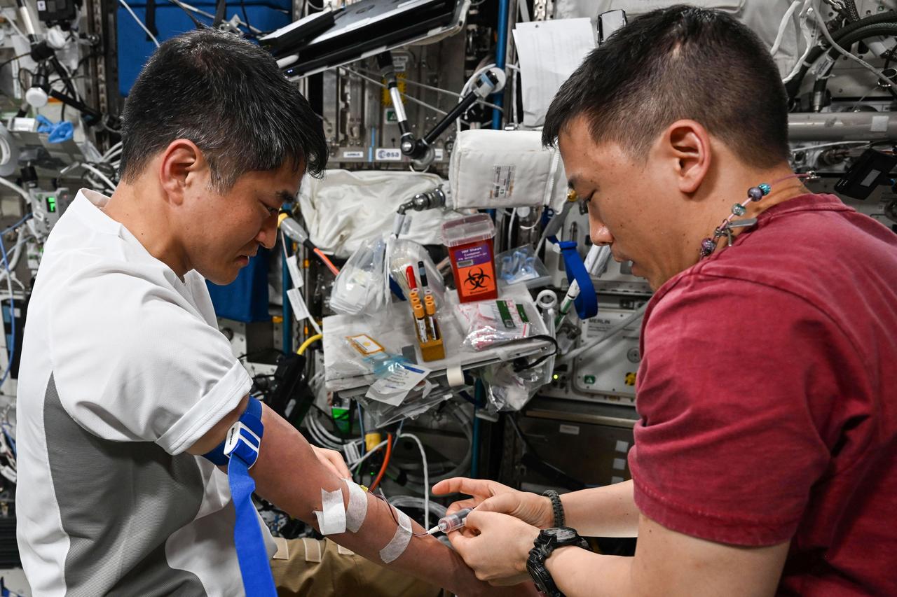 iss073e0384171 (July 1, 2025) --- Expedition 73 Flight Engineer Jonny Kim (right) of NASA draws a blood sample from station Commander Takuya Onishi of JAXA (Japan Aerospace Exploration Agency) for processing in a centrifuge and preservation in a science freezer. The samples will be returned to Earth where scientists will analyze the specimens to learn how living and working in microgravity affects the human body and provide countermeasures to potential space-caused symptoms.