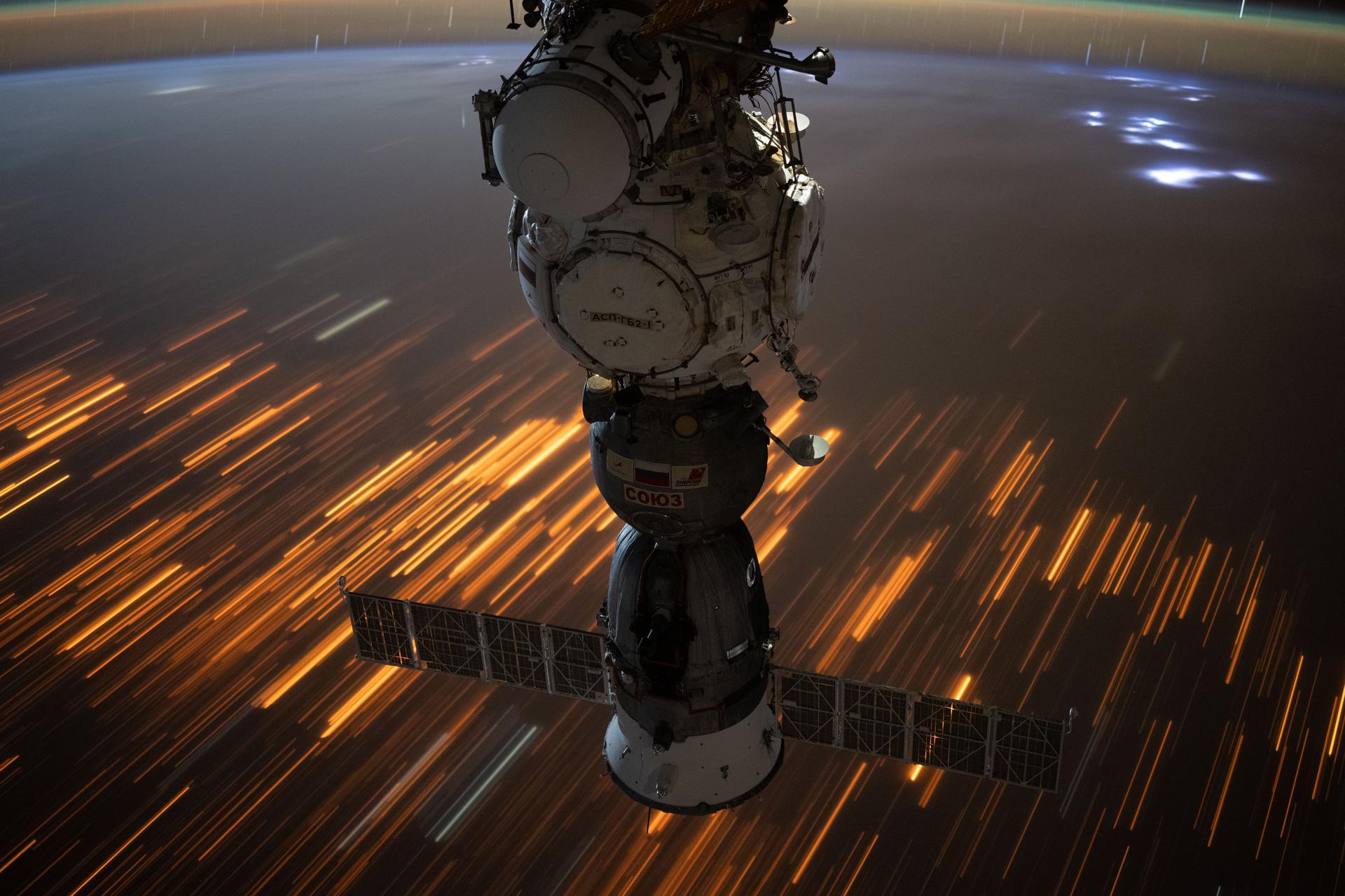 The city lights of Sub-Saharan Africa streak below the International Space Station as it orbited 260 miles above the Tanzania-Zambia border in this long-duration photograph. At top right, lightning storms illuminate the cloud tops with the Soyuz MS-27 spacecraft docked to the Prichal module in the foreground.