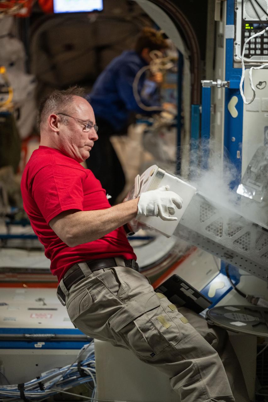 iss073e0424037 (Aug. 7, 2025) --- NASA astronaut and Expedition 73 Flight Engineer Mike Fincke inserts a cryogenic storage unit, called a dewar, containing blood samples collected from a crew member into a science freezer for preservation and later analysis. The Minus Eighty-Degree Laboratory Freezer for International Space Station, or MELFI, is a research freezer that maintains experiment samples at ultra-cold temperatures in microgravity.