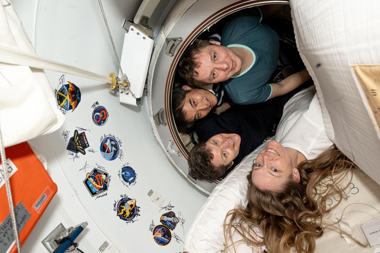 iss073e0426527 (Aug. 6, 2025) --- NASA's SpaceX Crew-10 members pose inside the vestibule between their SpaceX Dragon crew spacecraft and the International Space Station's forward port on the Harmony module. Clockwise from bottom are, NASA astronauts Nichole Ayers and Anne McClain, JAXA (Japan Aerospace Exploration Agency) astronaut Takuya Onishi, and Roscosmos cosmonaut Kirill Peskov. The walls of the vestibule are lined with mission stickers and crew signatures left by previous visitors who docked at Harmony’s forward port.