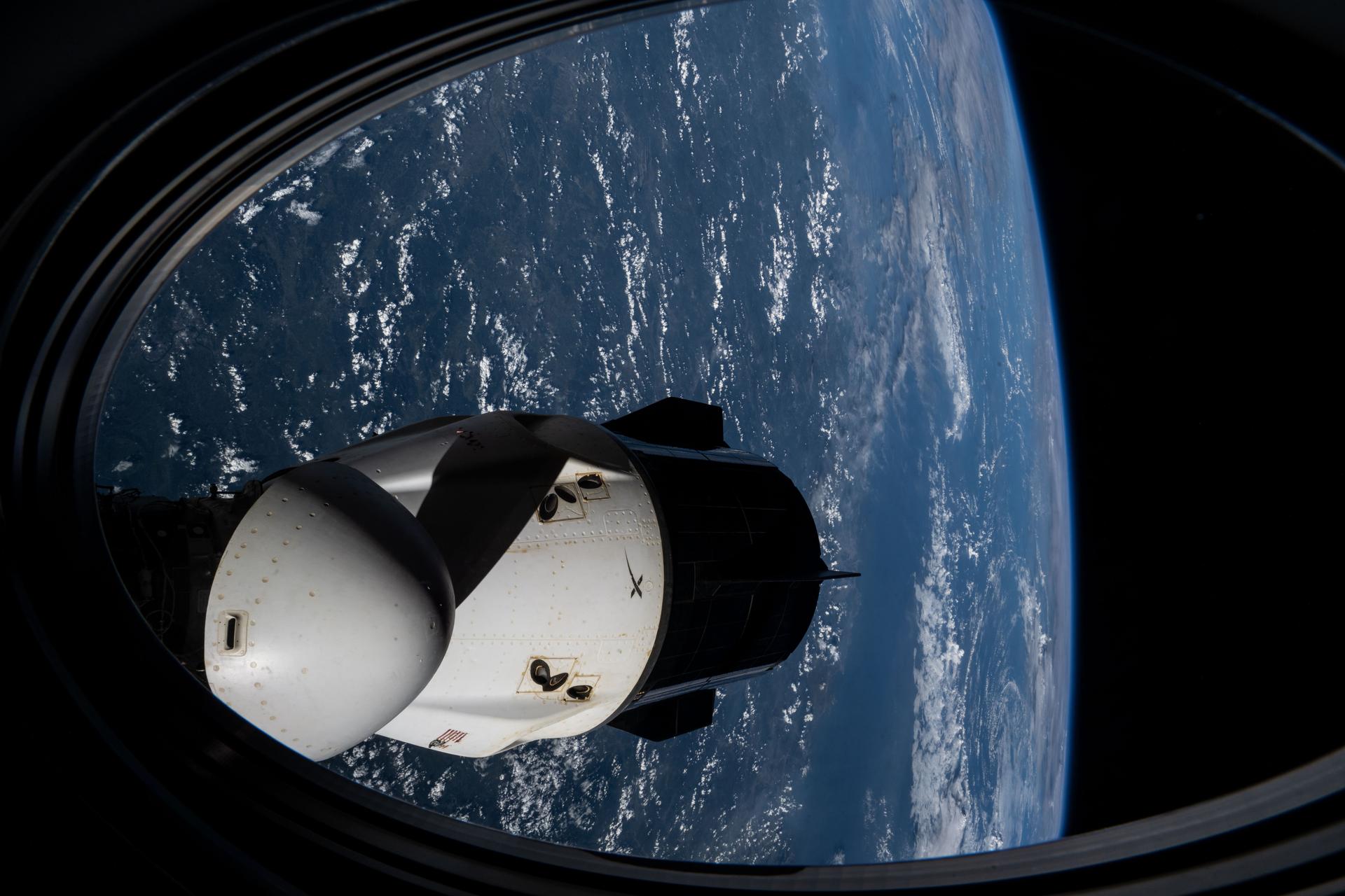From one Dragon to another: A view of the SpaceX Dragon crew spacecraft docked to the forward port of the International Space Station's Harmony module, captured from a window aboard another Dragon spacecraft docked to Harmony’s space-facing port.