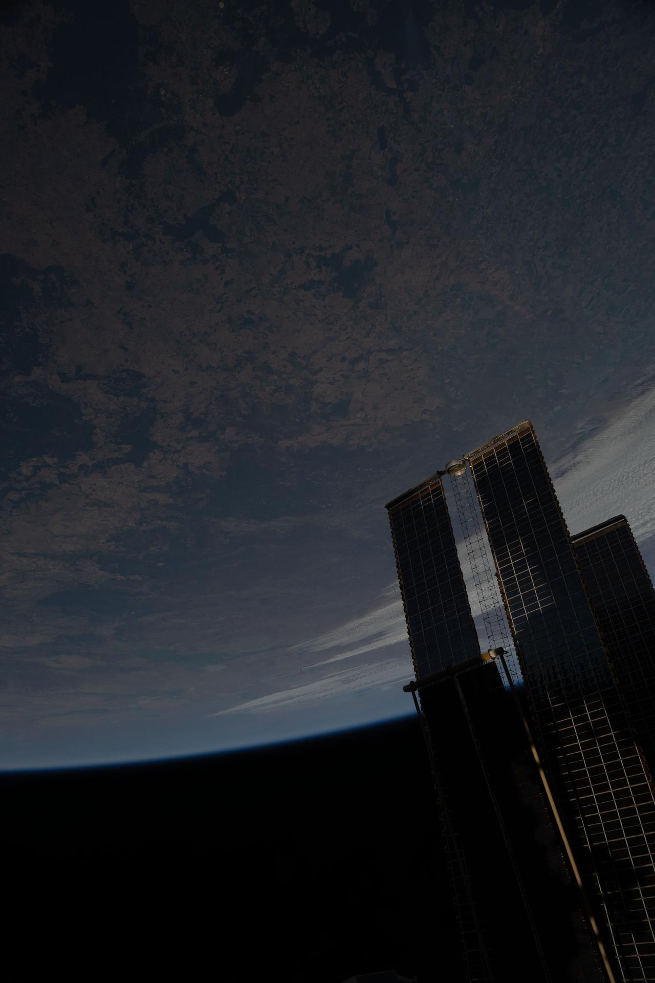 The International Space Station soared 264 miles above the hot, arid region of Australia's Queensland province. At lower right, is a set of the orbital outpost's main solar arrays and a rollout solar array.