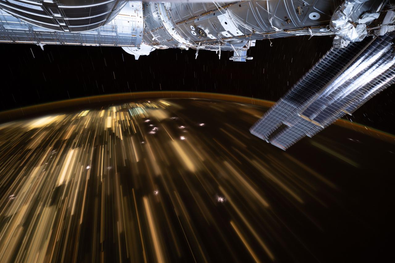 iss073e0507880 (July 26, 2025) --- The warm city lights of Southeast Asia streak below the silvery U.S. segment of the International Space Station in this 30-second exposure from the orbital outpost as it soared 259 miles above China at approximately 10:39 a.m. local time. Near the top center, is the partially obscured SpaceX Dragon spacecraft that docked to the Harmony module's forward port carrying NASA's Crew-11 mission.